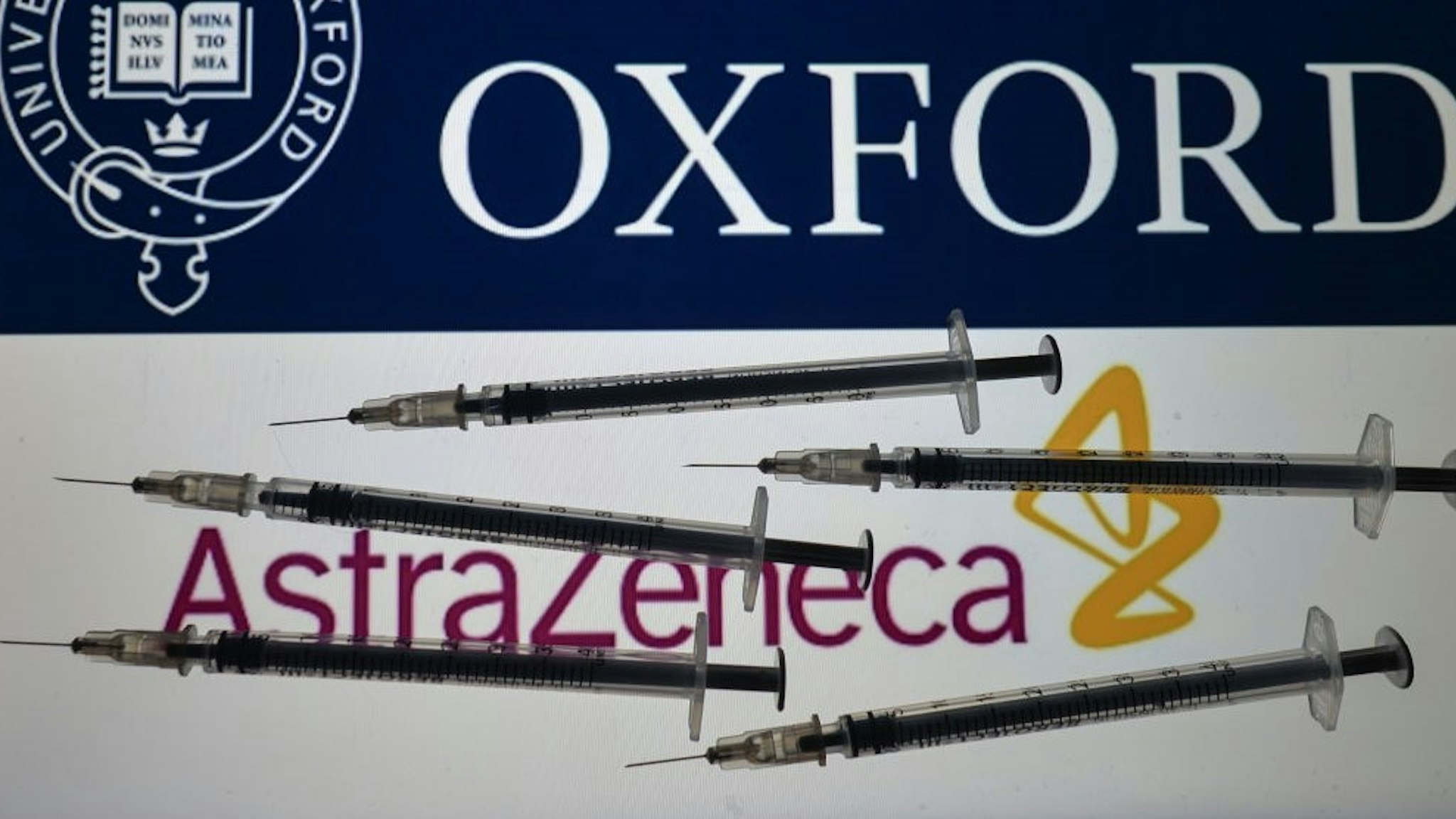 An illustrative photo showing a medical syringe seen in front of Pfizer-BionTech, Moderna and AstraZeneca-University of Oxford logos displayed on screens in the background on Christmas Eve. On Thursday, December 24, 2020, in Dublin, Ireland. (Photo illustration by
