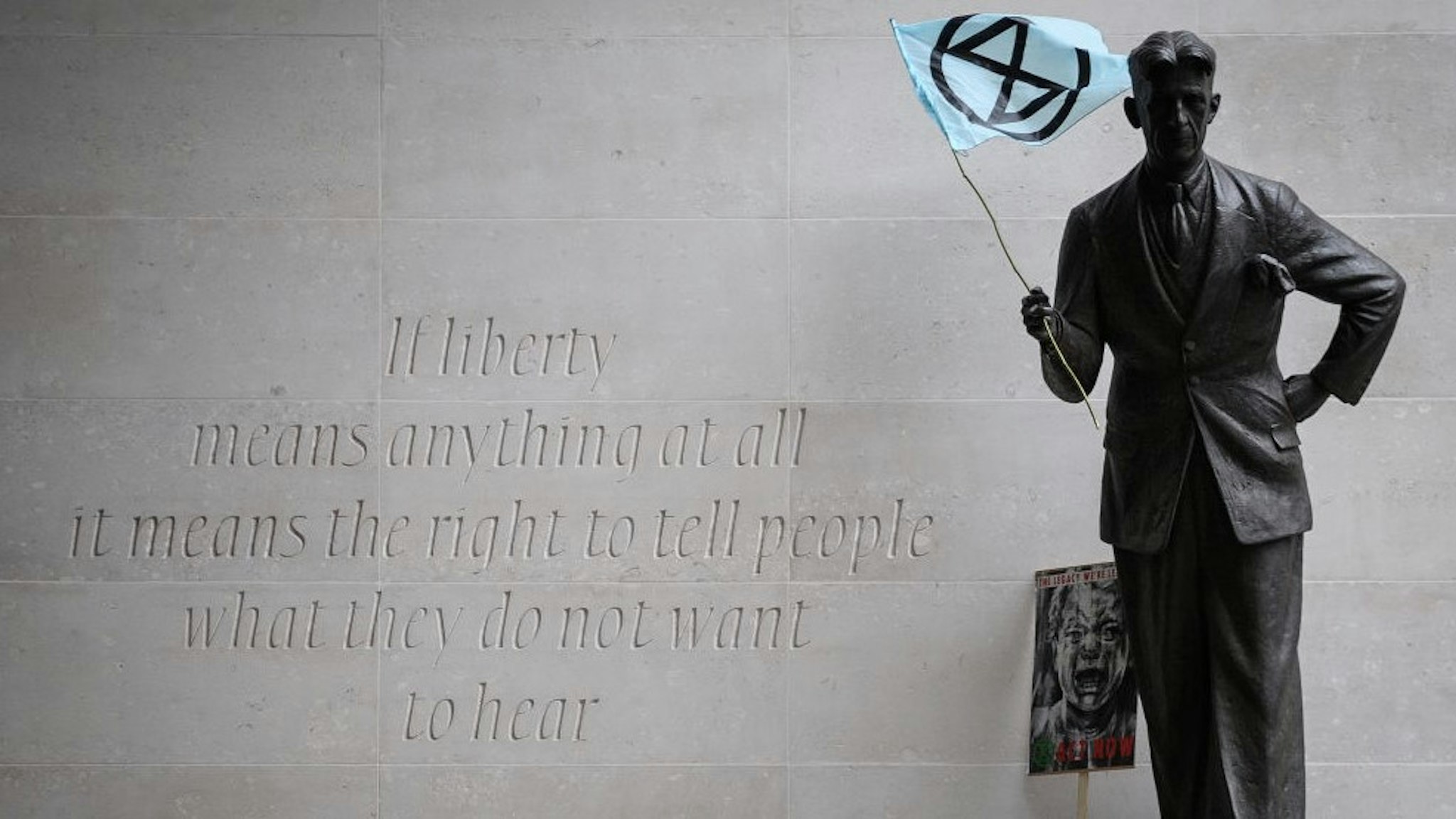 LONDON, ENGLAND - OCTOBER 11: An Extinction Rebellion flag is seen in the hands of a statue of author George Orwell outside the headquarters of the BBC as the environmental group protests about the broadcaster's alleged silence over climate issues on October 11, 2019 in London, England. The Extinction Rebellion group is in the middle of a string of protests across the country, with the aim of highlighting the urgency to address climate change as an ongoing emergency. (Photo by