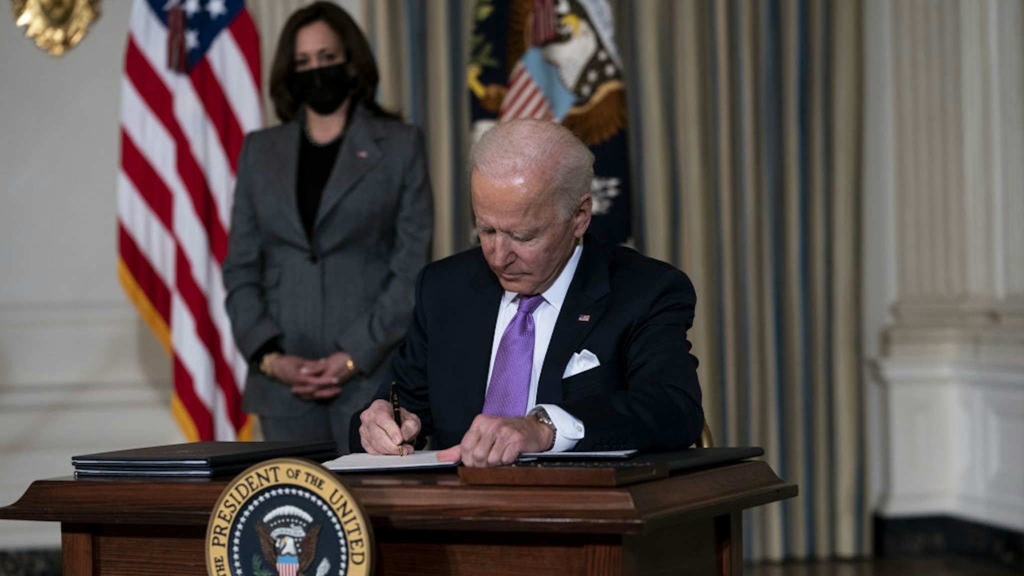 U.S. President Joe Biden signs an executive order in the State Dining Room of the White House in Washington, D.C., U.S., on Tuesday, Jan. 26, 2021.