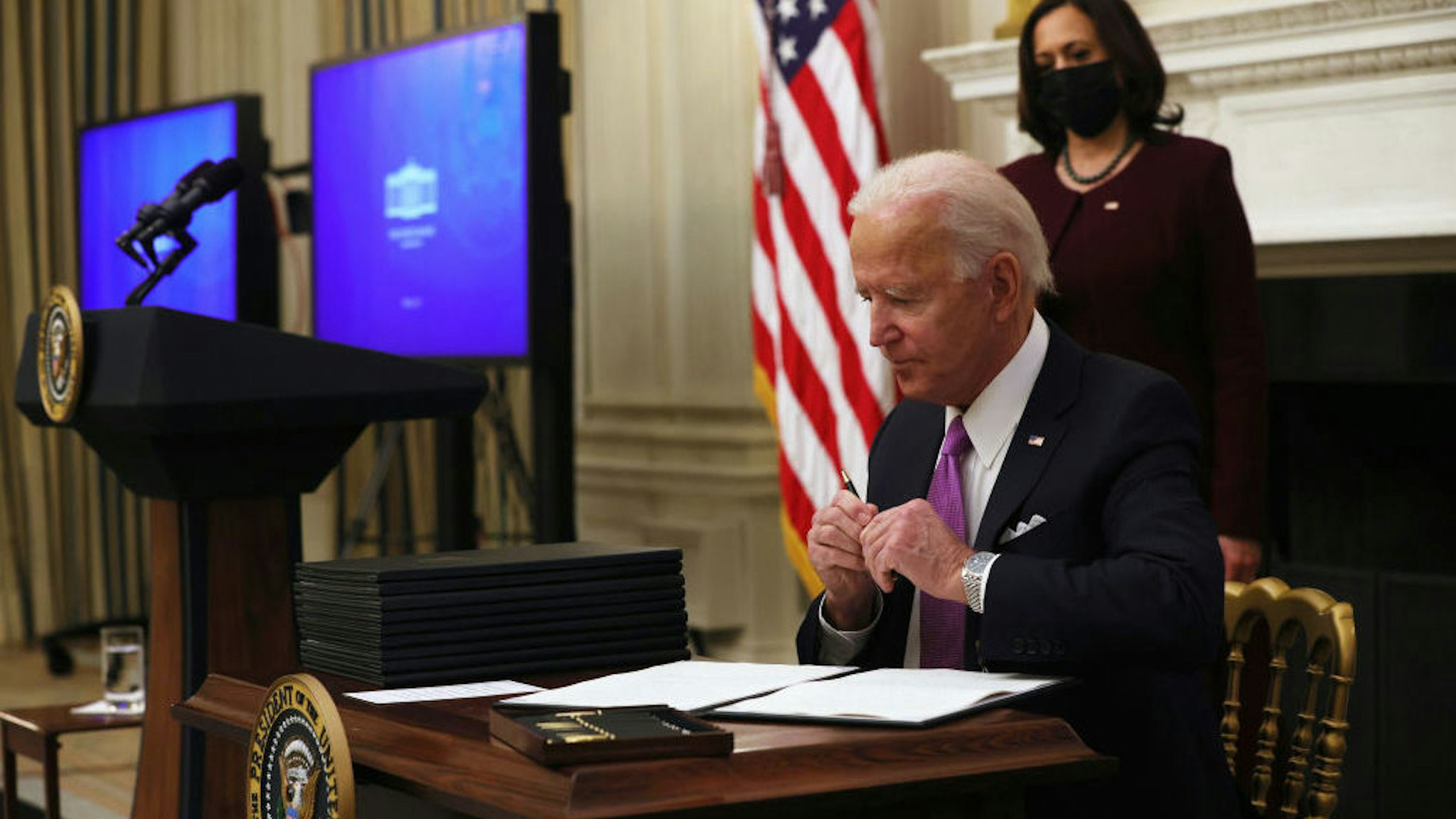 WASHINGTON, DC - JANUARY 21: U.S. President Joe Biden signs executive orders as Vice President Kamala Harris looks on during an event at the State Dining Room of the White House January 21, 2021 in Washington, DC. President Biden delivered remarks on his administration’s COVID-19 response, and signed executive orders and other presidential actions.