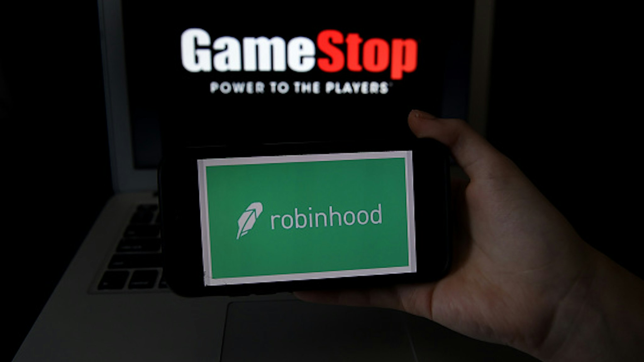 This photo illustration shows the logos of video grame retail store GameStop and trading application Robinhood on a computer and on a mobile phone in Arlington, Virginia on January 28, 2021. - An epic battle is unfolding on Wall Street, with a cast of characters clashing over the fate of GameStop, a struggling chain of video game retail stores. The conflict has sent GameStop on a stomach-churning ride with amateur investors taking on the financial establishment in the mindset of the Occupy Wall Street movement launched a decade ago.