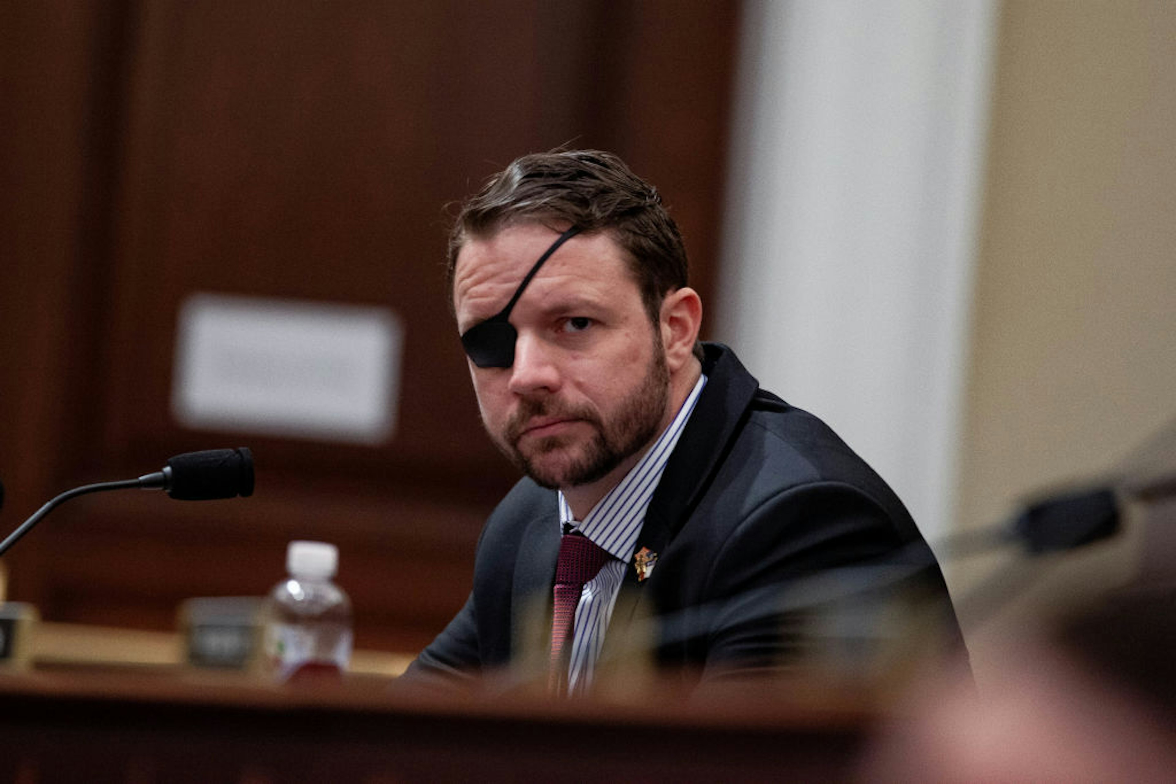 Representative Dan Crenshaw a Republican from Texas, listens during a House Budget Committee hearing with Russell Vought, acting director of the Office of Management and Budget (OMB), not pictured, in Washington, D.C., U.S., on Tuesday, March 12, 2019. President Donald Trump will propose a U.S. budget that wouldn't balance for 15 years, even assuming stronger economic growth than private forecasters expect and with deep domestic spending cuts that have little chance of passing Congress. Vought said in a statement the proposal "embodies fiscal responsibility" and "shows that we can return to fiscal sanity without halting our economic resurgence." Photographer: Anna Moneymaker/Bloomberg via Getty Images
