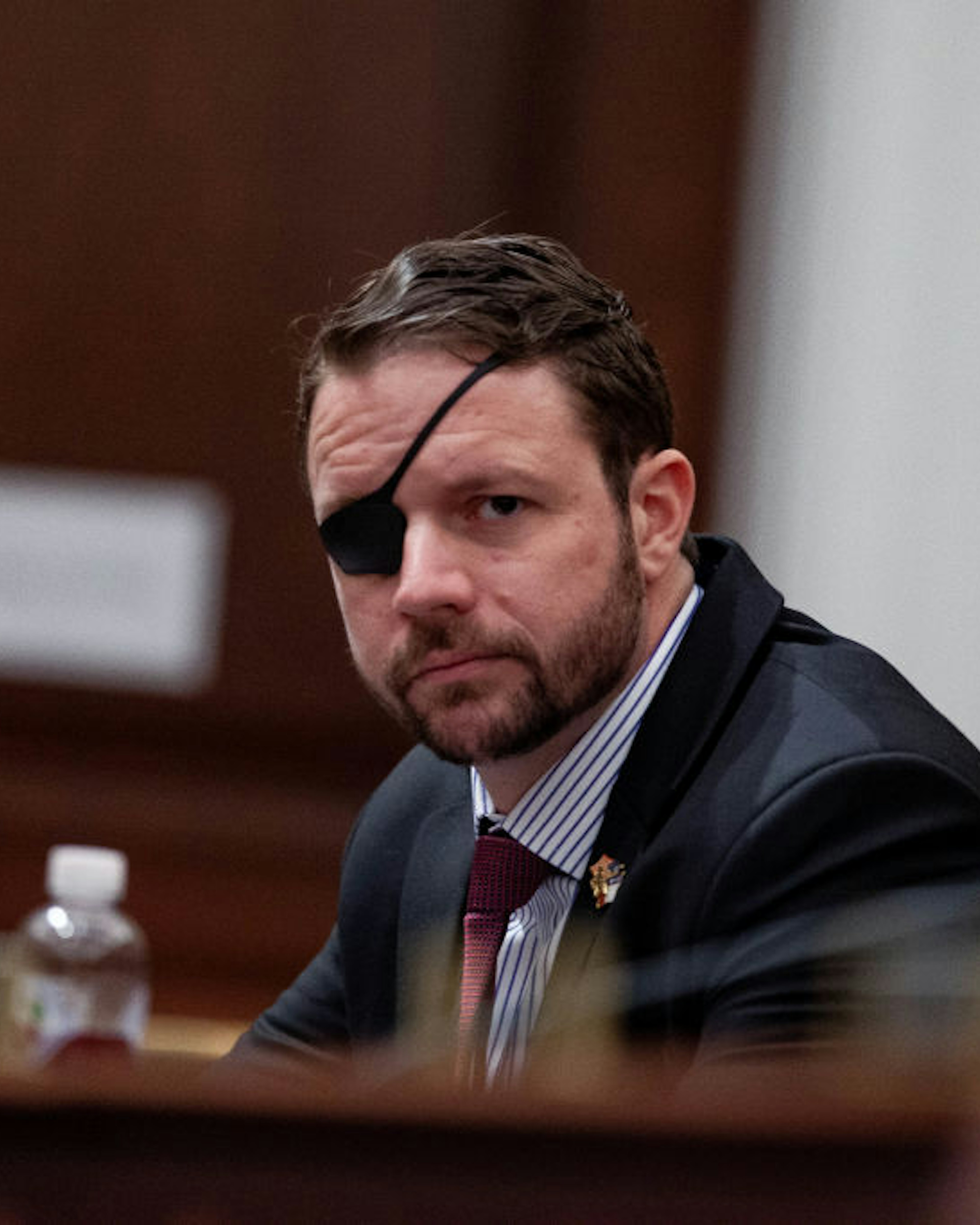 Representative Dan Crenshaw a Republican from Texas, listens during a House Budget Committee hearing with Russell Vought, acting director of the Office of Management and Budget (OMB), not pictured, in Washington, D.C., U.S., on Tuesday, March 12, 2019. President Donald Trump will propose a U.S. budget that wouldn't balance for 15 years, even assuming stronger economic growth than private forecasters expect and with deep domestic spending cuts that have little chance of passing Congress. Vought said in a statement the proposal "embodies fiscal responsibility" and "shows that we can return to fiscal sanity without halting our economic resurgence." Photographer: Anna Moneymaker/Bloomberg via Getty Images