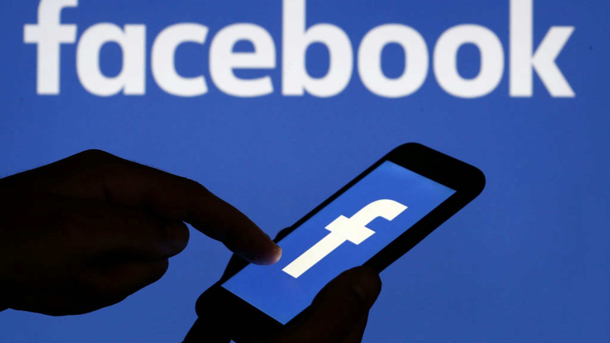 In this photo illustration, the Facebook logo is displayed on the screen of a smartphone in front of a computer screen displaying the logo of Facebook on September 09, 2019 in Paris, France.