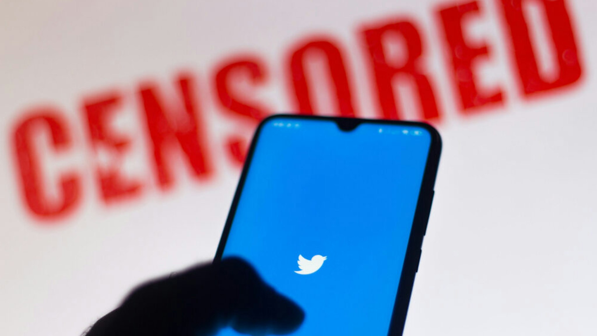 BRAZIL - 2020/06/15: In this photo illustration the Twitter logo is displayed on a smartphone and a red alerting word "CENSORED" on the blurred background.