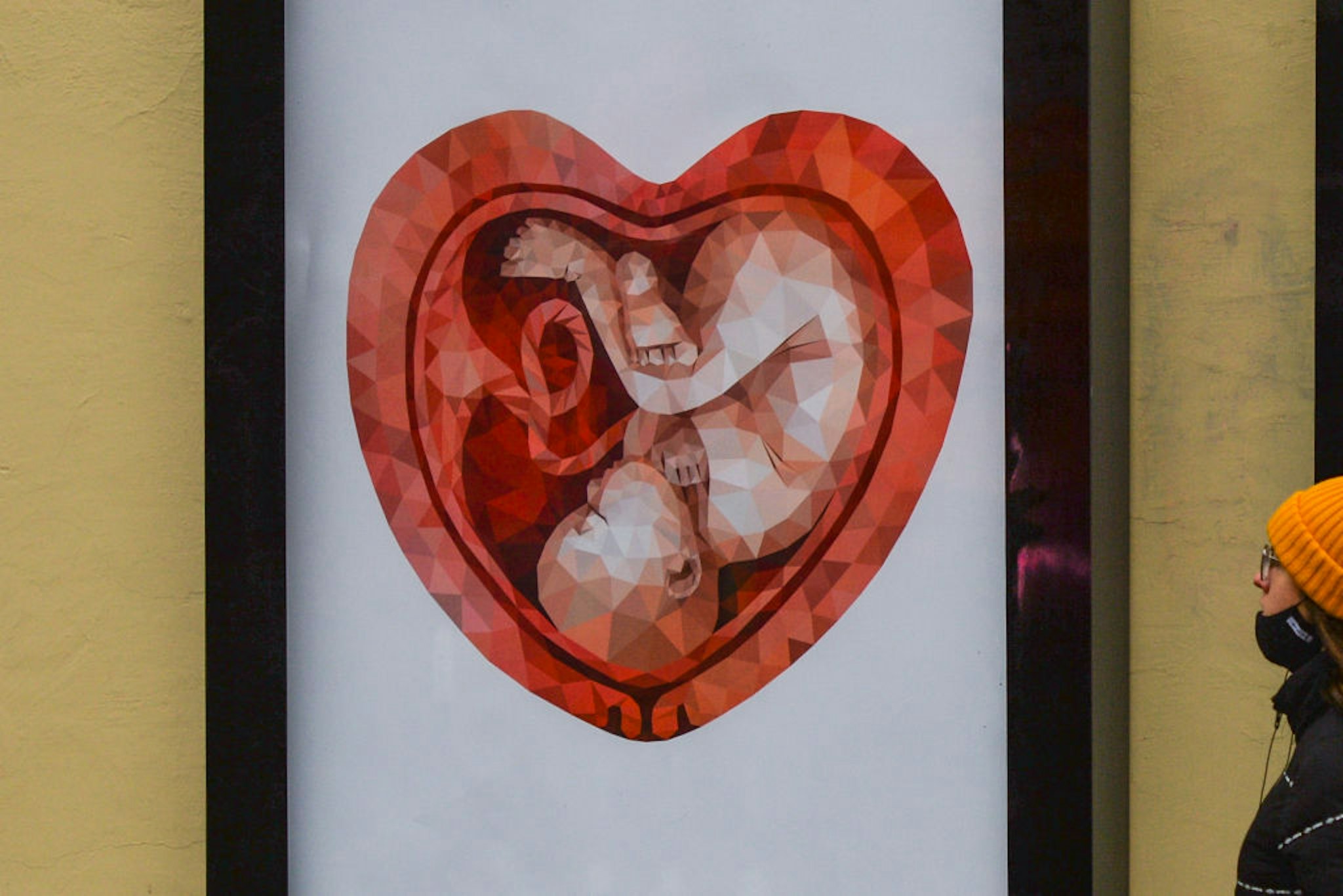 A lady passes next to a vandalised billboard with an image of a fetus inside a heart shaped womb, by Ekaterina Glazkova, seen in Krakow (photo taken on December 9, 2020 in Krakow). 30-year-old independent artist Ekaterina Glazkova from St. Petersburg unexpectedly became famous in Poland thanks to the Foundation 'Our Children - Education, Health, Faith' from Kornice in Silesia. The drawing of a Russian woman - a child in the womb - appearing on billboards and posters in various Polish cities has become a symbol of the anti-abortion movement. However, as per the artist's statement on Instagram on December 11, the intended purpose of the illustration was not related to the Pro-Life movement: 'This illustration was painted as something positive, as the personification of the joy of motherhood, but definitely not a symbol of the oppression of women's human rights. I've been selling this picture on microstocks for many years now, and in theory anyone can buy it and use it. But Ive never thought that everything could turn out like this. As for myself, I can say that, as a woman and as an artist, I fully support Polish women in their struggle for their right to make choices'. On Wednesday, December 16, 2020, in Dublin, Ireland. (Photo by Artur Widak/NurPhoto via Getty Images)