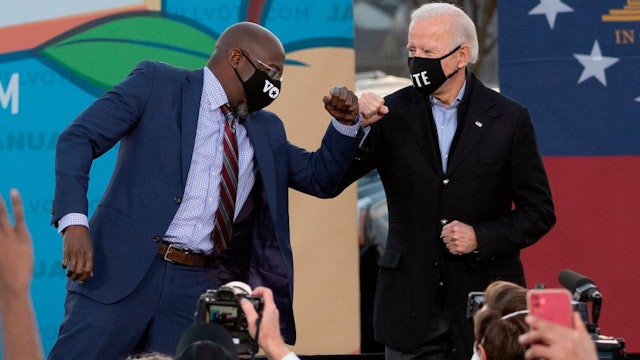 Democratic candidate for Senate Raphael Warnock (L) and US President-elect Joe Biden (R) bump elbows on stage during a rally outside Center Parc Stadium in Atlanta, Georgia, on January 4, 2021