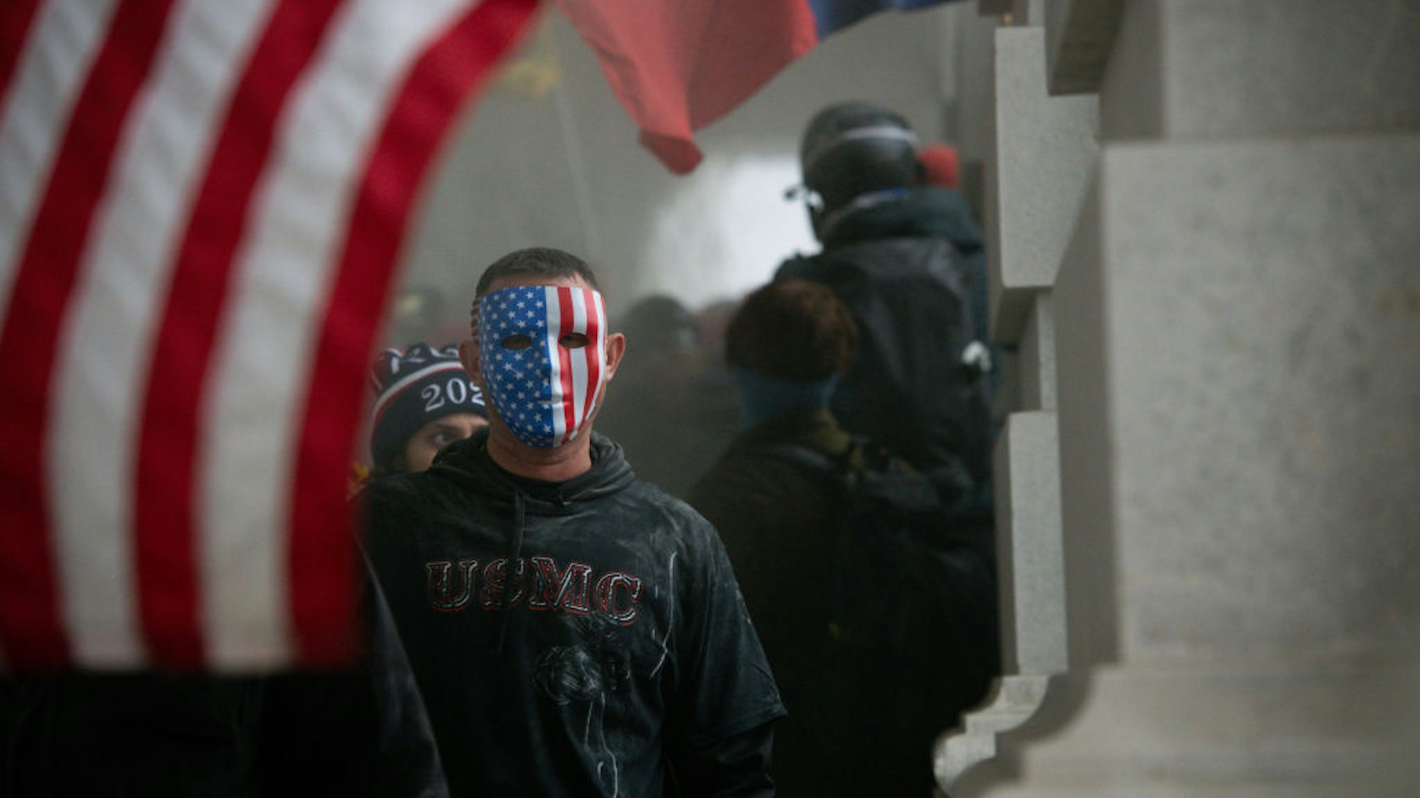 A demonstrator wears an American flag mask during a protest at the U.S. Capitol in Washington, D.C., U.S., on Jan. 6, 2021. The U.S. Capitol was placed under lockdown and Vice President Mike Pence left the floor of Congress as hundreds of protesters swarmed past barricades surrounding the building where lawmakers were debating Joe Biden's victory in the Electoral College. Photographer: Graeme Sloan/Bloomberg via Getty Images
