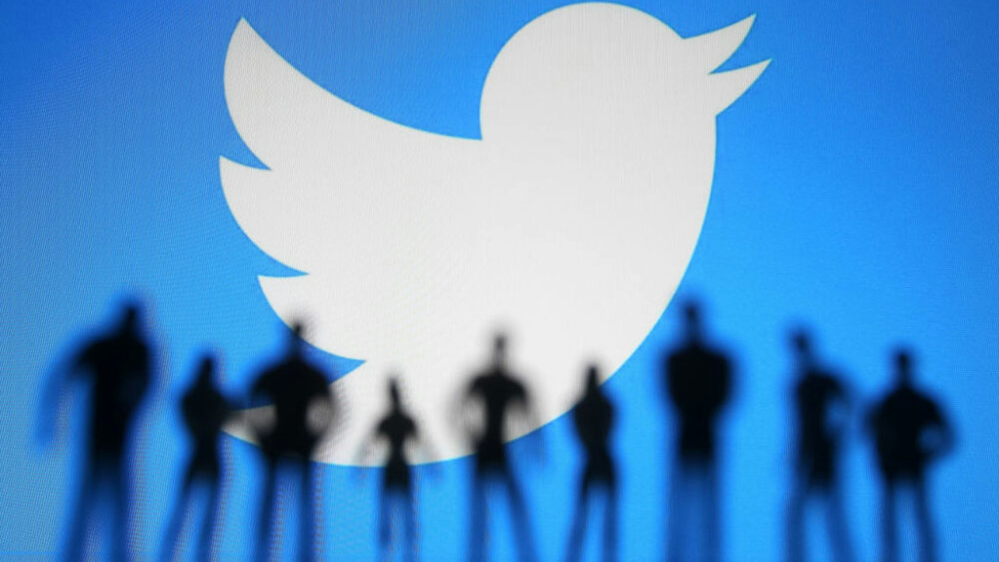UKRAINE - 2021/01/11: In this photo illustration a Twitter logo is seen displayed in front of the silhouettes of toy people.