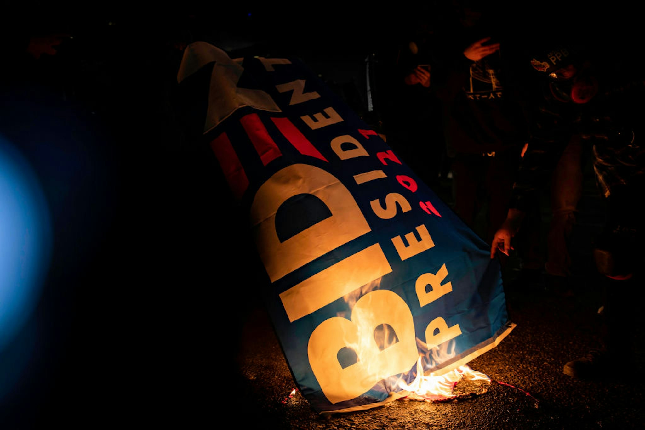 PORTLAND, OR, UNITED STATES - JANUARY 20: Protesters burn a Biden for President flag outside of the Federal Immigration and Customs Enforcement [ICE] building in Portland, Oregon on January 20, 2021. (Photo by Maranie R. Staab for The Washington Post via Getty Images)