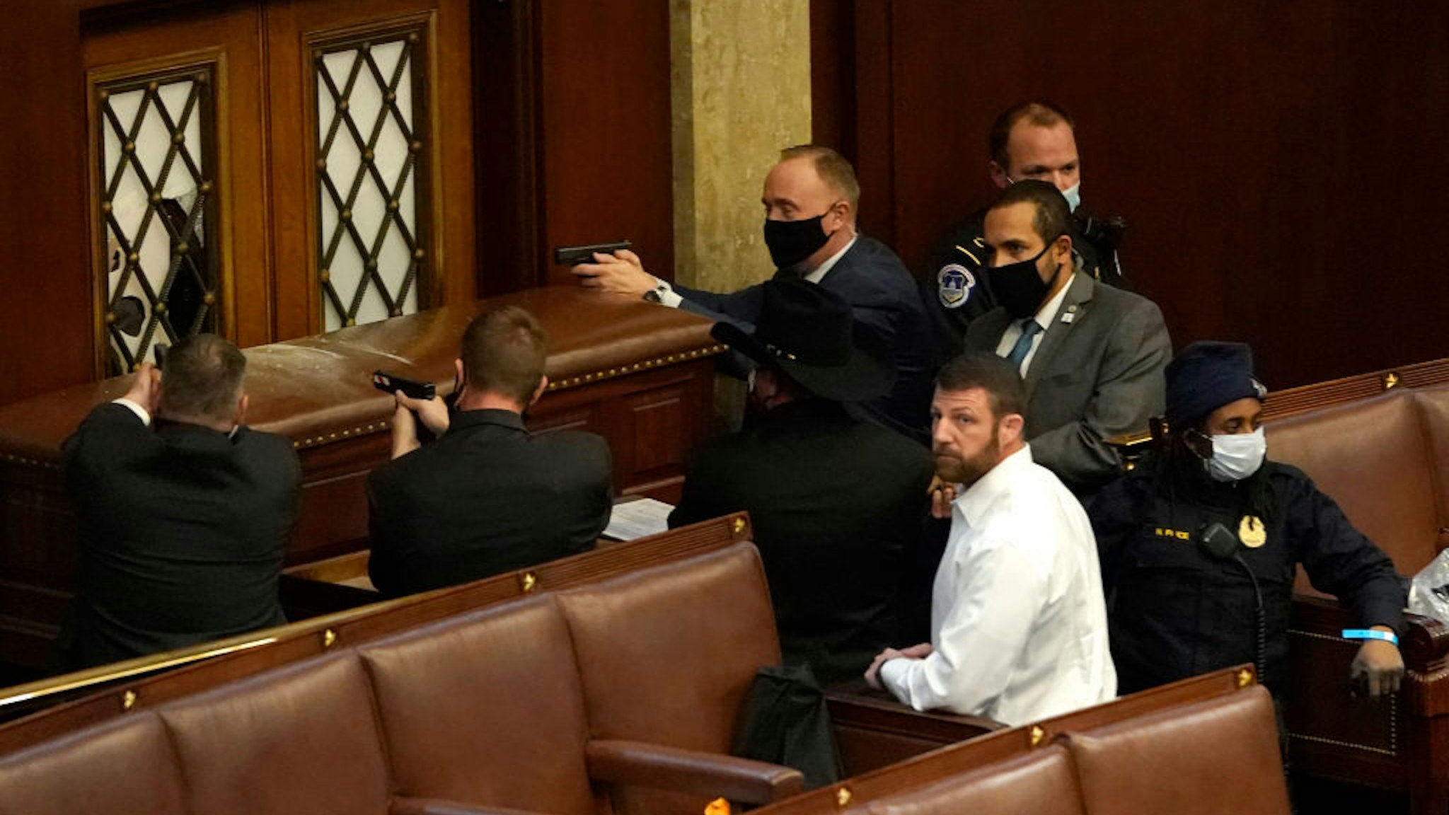 WASHINGTON, DC - JANUARY 06: U.S. Capitol police officers point their guns at a door that was vandalized in the House Chamber during a joint session of Congress on January 06, 2021 in Washington, DC. Congress held a joint session today to ratify President-elect Joe Biden's 306-232 Electoral College win over President Donald Trump. A group of Republican senators said they would reject the Electoral College votes of several states unless Congress appointed a commission to audit the election results. (Photo by Drew Angerer/Getty Images)