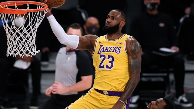 LeBron James #23 of the Los Angeles Lakers scores on a layup past Andrew Wiggins #22 of the Golden State Warriors during the first half at Staples Center on January 18, 2021 in Los Angeles, California.
