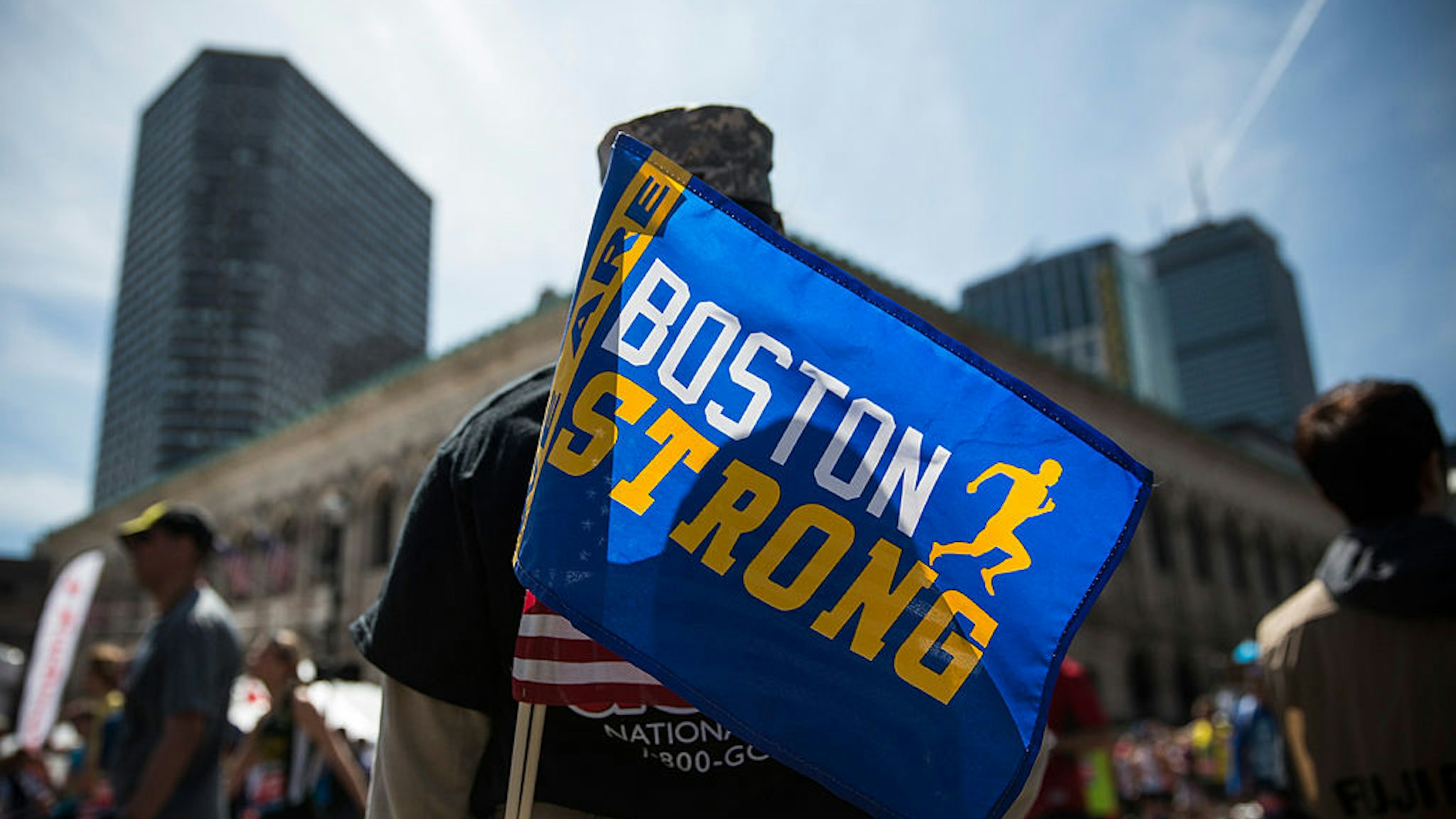 A soldier in the National Guard with a "Boston Strong" flag cheers on runners as they finish the Boston Marathon on April 21, 2014 in Boston, Massachusetts.