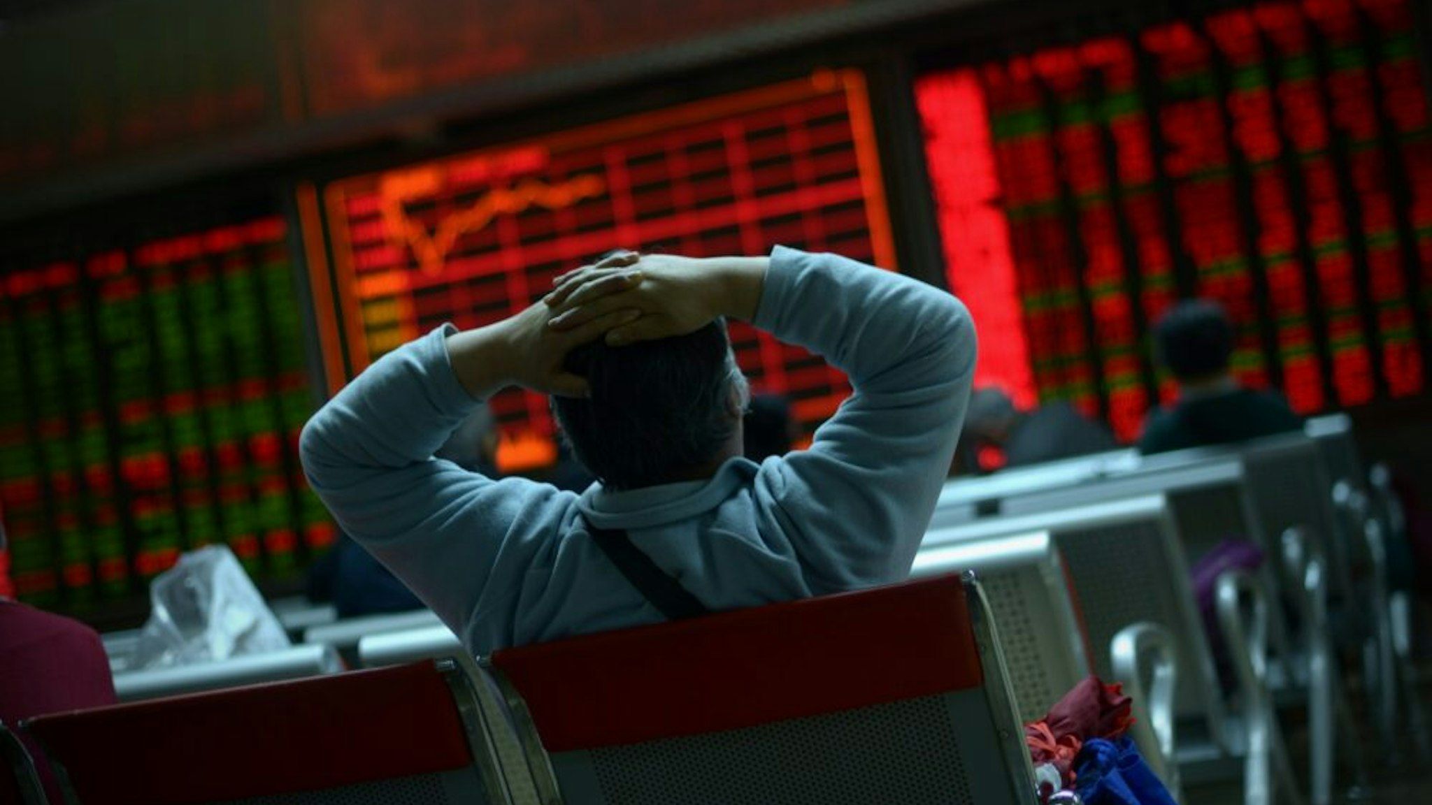TOPSHOT - An investor looks at screens showing stock market movements at a securities company in Beijing on January 8, 2016. Chinese equities led another day of volatility across Asia on January 8 as investors were panicked by Beijing's attempts to stabilise its beleaguered markets, with fears growing the global economy could be teetering.