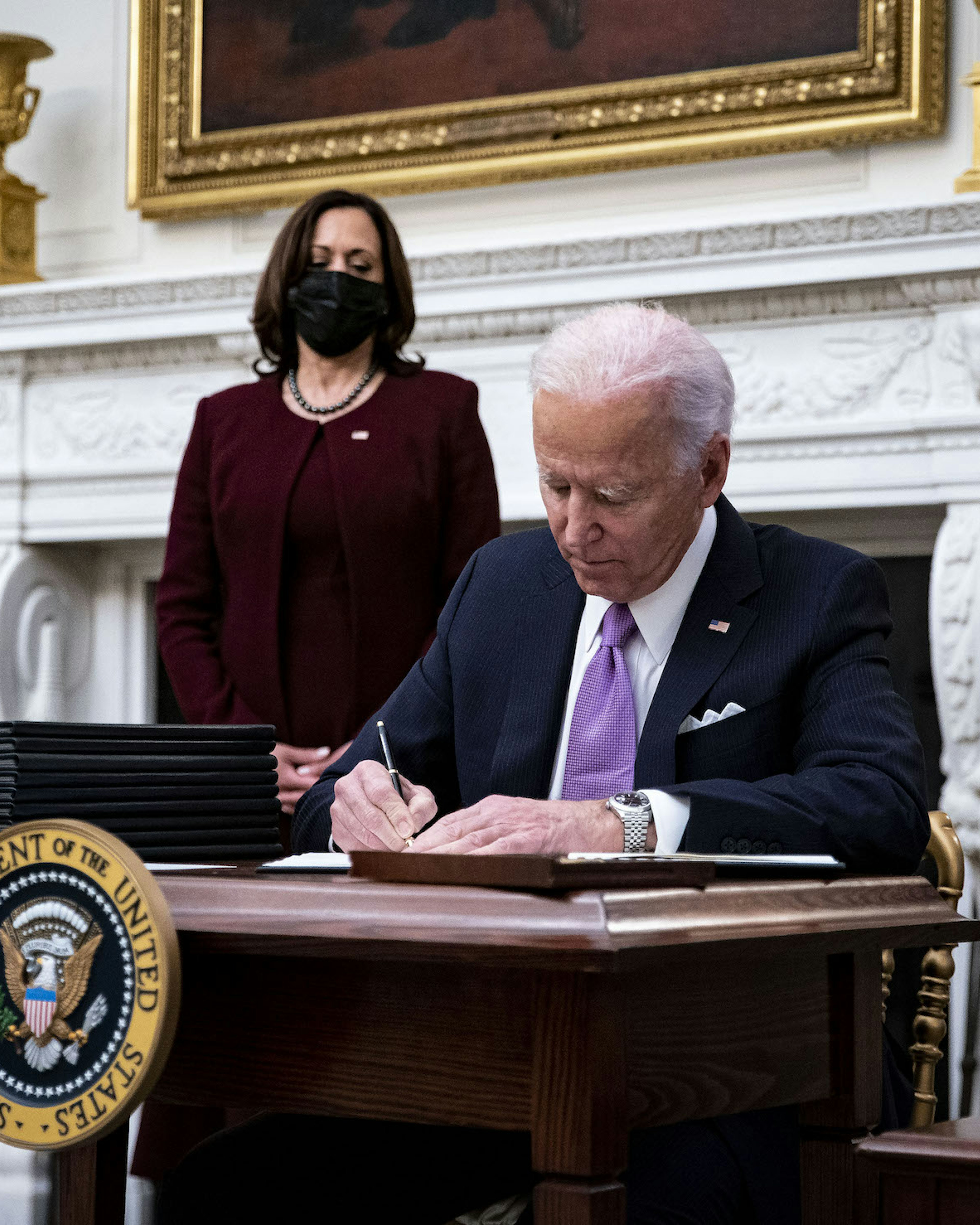 U.S. President Joe Biden signs an executive order after speaking during an event on his administration's Covid-19 response with U.S. Vice President Kamala Harris, left, in the State Dining Room of the White House in Washington, D.C., U.S., on Thursday, Jan. 21, 2021. Biden in his first full day in office plans to issue a sweeping set of executive orders to tackle the raging Covid-19 pandemic that will rapidly reverse or refashion many of his predecessor's most heavily criticized policies. Photographer: Al Drago/Bloomberg