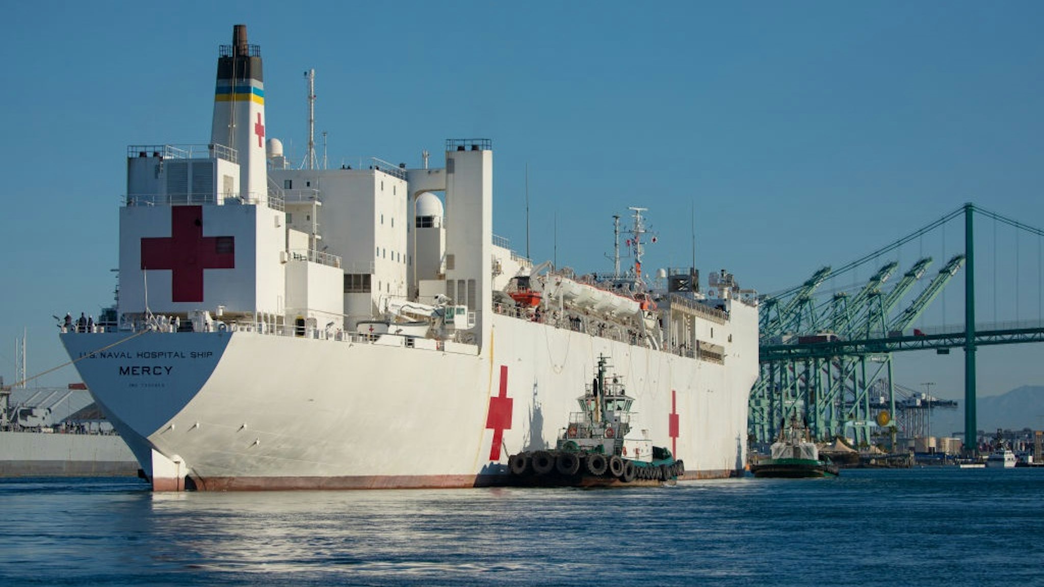Tugboats guide the USNS Mercy hospital ship to moor at the Port of Los Angeles in Los Angeles, California, U.S., on Friday, March 27, 2020.