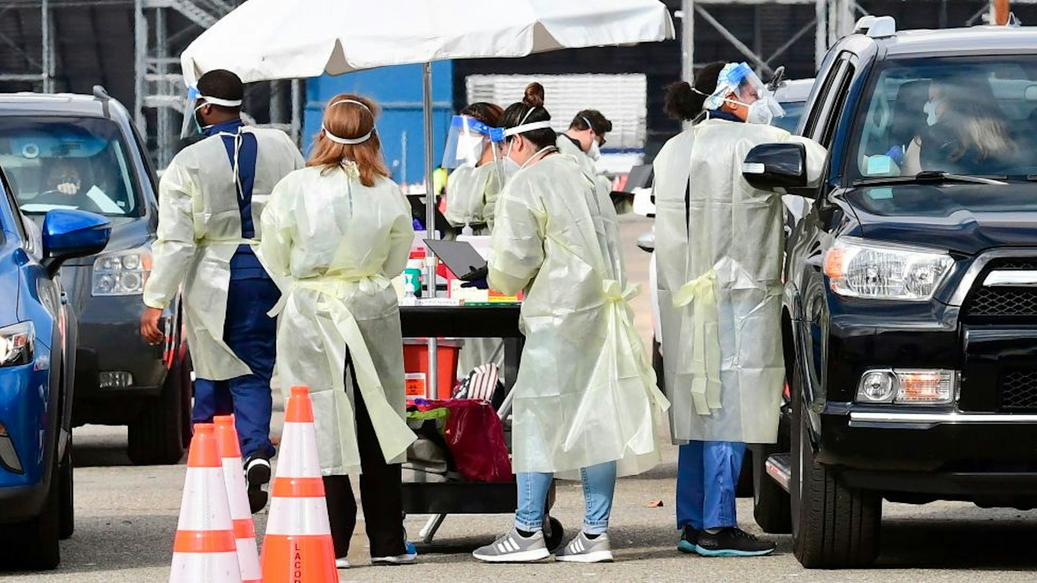 Healthcare personel dressed in personal protective gear help inoculate people arriving to receive Covid-19 vaccines at the Fairplex in Pomona, California on January 22, 2021, one of five mass Covid-19 vaccine sites opened across Los Angeles County this week. - A severely limited supply of Covid-19 vaccines, which only recently became available to the population, could mean people won't be fully inoculated until 2022 unless the supply of the vaccine increases.