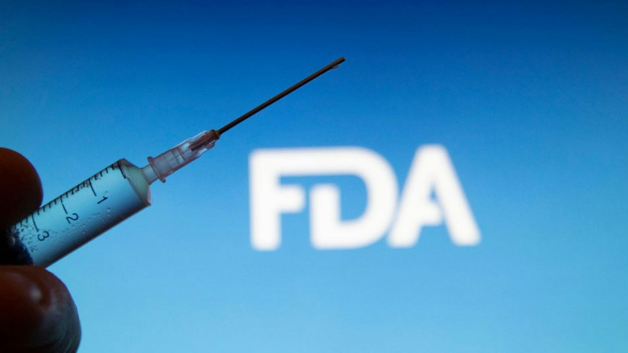 NETHERLANDS - 2020/12/30: In this photo illustration a medical syringe is seen with FDA logo ( Food and Drug Administration of the United States ) FDA approved Pfizer / BioNTech and Moderna COVID-19 coronavirus vaccine for emergency use in the US, with an emergency use authorization (EUA). (Photo Illustration by
