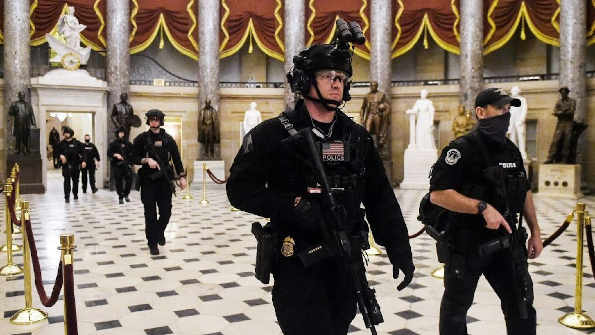 Members of the Swat team patrol and secure the Statuary Hall before US Vice President makes his way into the House Chamber, at the US Capitol, on January 7, 2021 in Washington, DC. - Congress was on track on January 7, 2021 to certify Joe Biden as the next US president and deal a hammer blow to Donald Trump whose supporters stormed the Capitol hours earlier, triggering unprecedented chaos and violence in the seat of American democracy. (Photo by