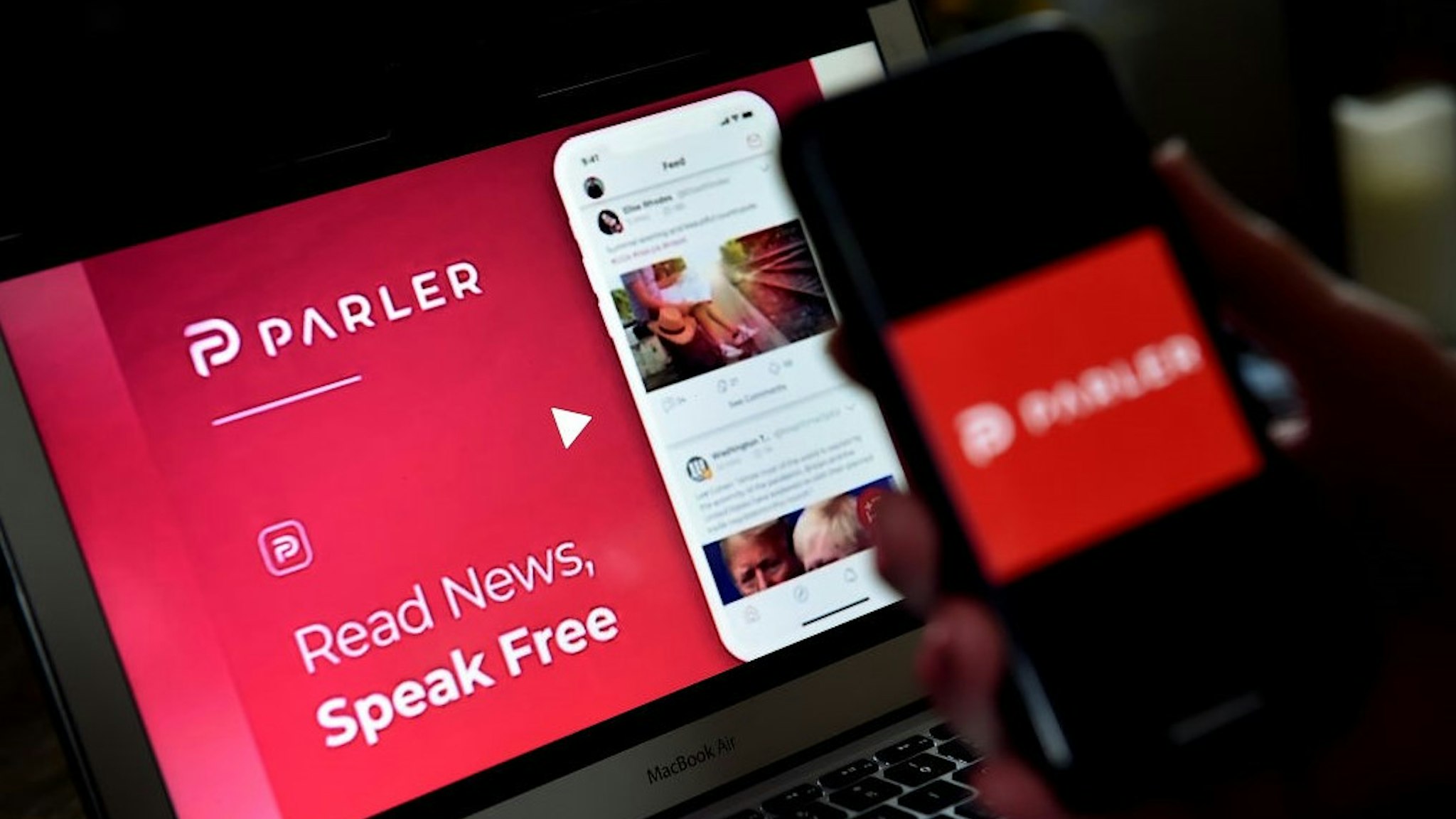 This illustration picture shows social media application logo from Parler displayed on a smartphone with its website in the background in Arlington, Virginia on July 2, 2020. - Amid rising turmoil in social media, recently formed social network Parler is gaining with prominent political conservatives who claim their voices are being silenced by Silicon Valley giants. Parler, founded in Nevada in 2018, bills itself as an alternative to "ideological suppression" at other social networks. (Photo by Olivier DOULIERY / AFP) (Photo by