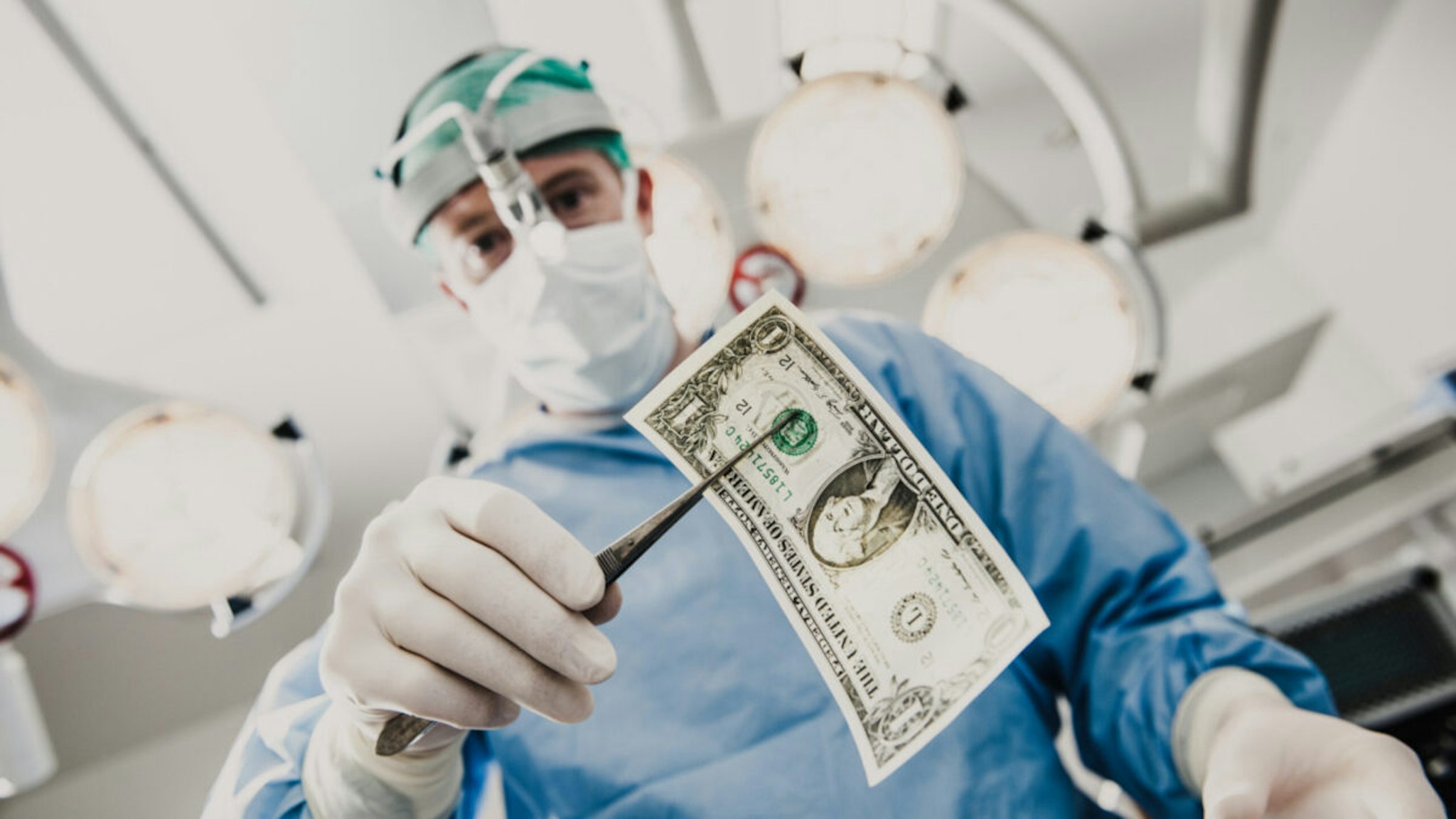 Doctor doing surgery in hospital with money - stock photo.