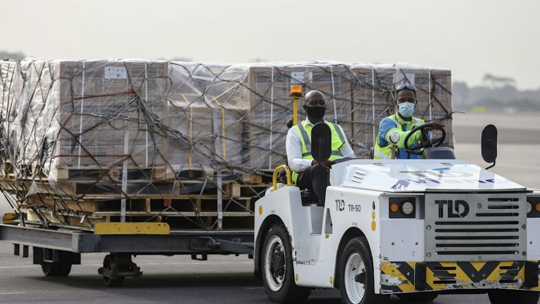 Airport workers transport on dollies a shipment of Covid-19 vaccines from the Covax global Covid-19 vaccination programme, at the Kotoka International Airport in Accra on February 24, 2021. - Ghana received the first shipment of Covid-19 vaccines from Covax, a global scheme to procure and distribute inoculations for free, as the world races to contain the pandemic. Covax, launched last April to help ensure a fairer distribution of coronavirus vaccines between rich and poor nations, said it would deliver two billion doses to its members by the end of the year. (Photo by Nipah Dennis / AFP) (Photo by NIPAH DENNIS/AFP via Getty Images)