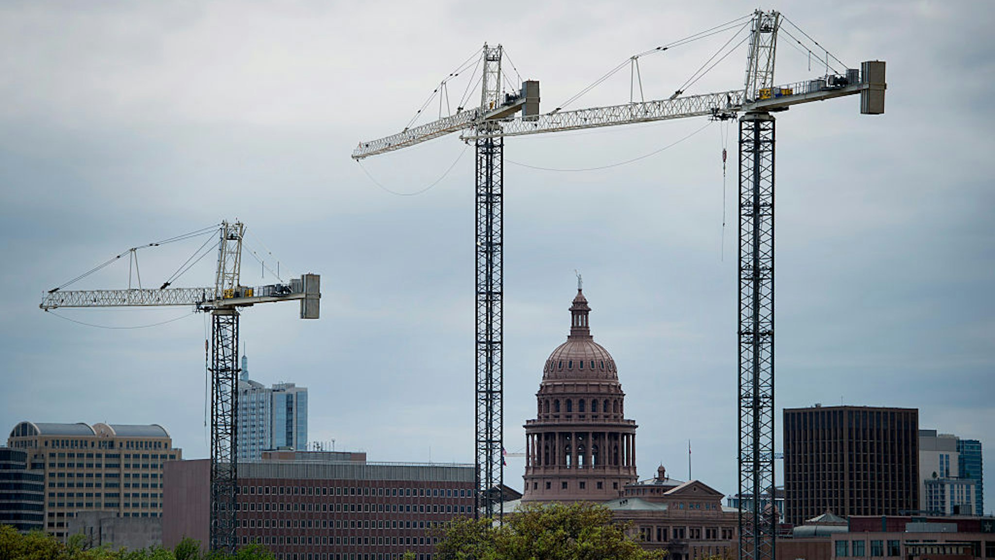 The Texas State Capitol building stands past construction cranes at the University of Texas at Austin campus in Austin, Texas, U.S., on Saturday, April 4, 2015. About 900,000 people live in the city of Austin and that number is expected to reach nearly 1.3 million by 2040, a 40 percent increase, according to city figures. More than 100 people move to the city a day, according to the city's demographer.