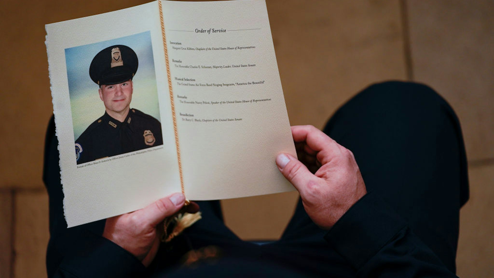 WASHINGTON, DC - FEBRUARY 3: A U.S. Capitol Police Officer holds a program for the ceremony memorializing U.S. Capitol Police Officer Brian D. Sicknick, 42, as he lies in honor in the Rotunda of the Capitol on February 3, 2021 in Washington DC. Officer Sicknick died as a result of injuries he sustained during the January 6 attack on the U.S. Capitol. He will lie in honor until February 3 and then be buried at Arlington National Cemetery.