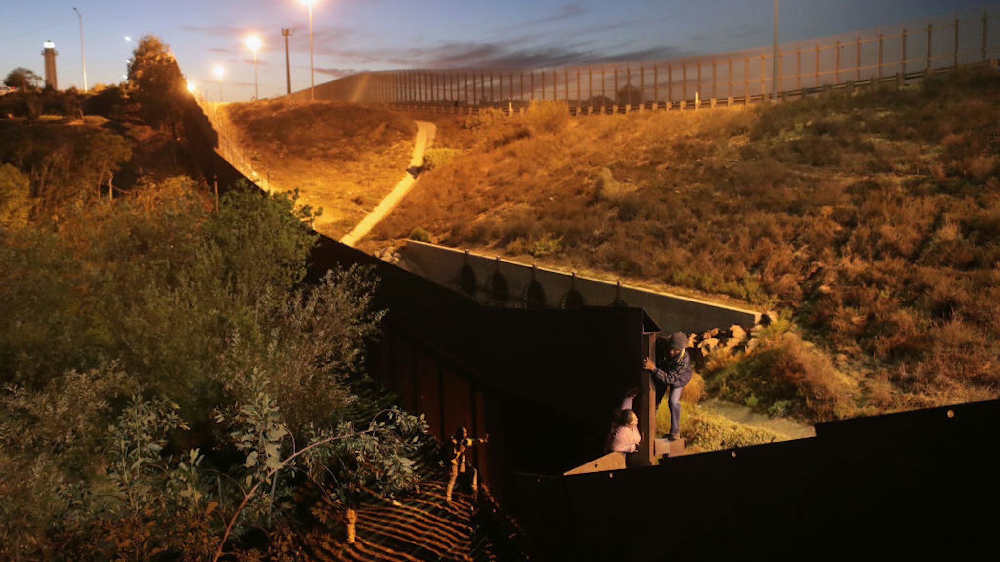 Members of the migrant caravan climb over the U.S.-Mexico border fence on December 3, 2018 from Tijuana, Mexico.
