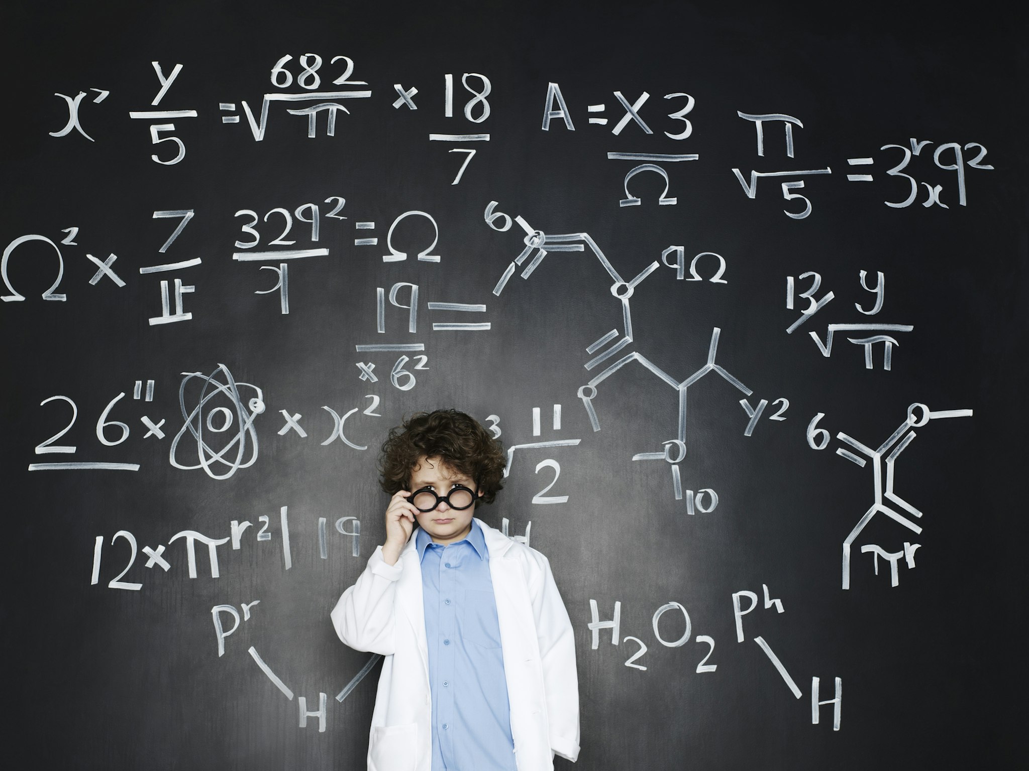 Boy as a professor with formulas behind him - stock photo