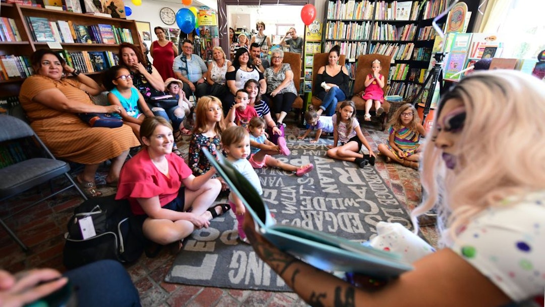 Drag queen Scalene Onixxx reads to adults and children during Drag Queen Story Hour at Cellar Door Books in Riverside, California on June 22, 2019. - Athena and Scalene, their long blonde hair flowing down to their sequined leotards and rainbow dresses, are reading to around 15 children at a bookstore in Riverside. The scene would be unremarkable -- except that they are both drag queens. The reading workshop is part of "Drag Queen Story Hour," an initiative launched in 2015 by a handful of libraries and schools across the United States. (Photo by Frederic J. BROWN / AFP) (Photo credit should read FREDERIC J. BROWN/AFP via Getty Images)