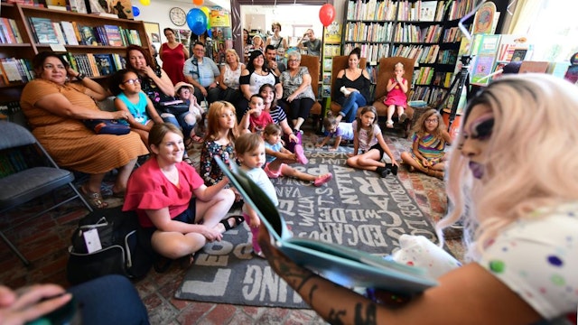 Drag queen Scalene Onixxx reads to adults and children during Drag Queen Story Hour at Cellar Door Books in Riverside, California on June 22, 2019. - Athena and Scalene, their long blonde hair flowing down to their sequined leotards and rainbow dresses, are reading to around 15 children at a bookstore in Riverside. The scene would be unremarkable -- except that they are both drag queens. The reading workshop is part of "Drag Queen Story Hour," an initiative launched in 2015 by a handful of libraries and schools across the United States. (Photo by Frederic J. BROWN / AFP) (Photo credit should read FREDERIC J. BROWN/AFP via Getty Images)