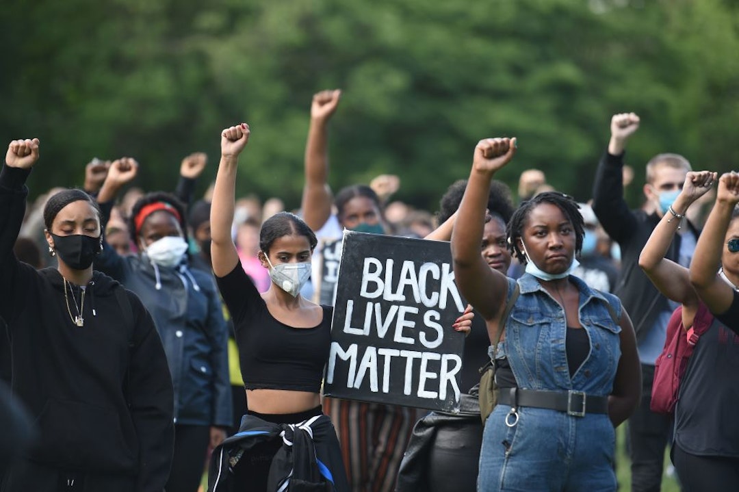 TOPSHOT - Protesters hold up fists at a gathering in support of the Black Lives Matter movement on Woodhouse Moor in Leeds in northern England on June 21, 2020, in the aftermath of the death of unarmed black man George Floyd in police custody in the US. (Photo by Oli SCARFF / AFP) (Photo by OLI SCARFF/AFP via Getty Images)