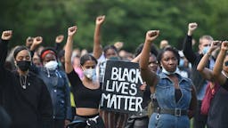 TOPSHOT-BRITAIN-POLITICS-POLICE-PROTEST-RACISM TOPSHOT - Protesters hold up fists at a gathering in support of the Black Lives Matter movement on Woodhouse Moor in Leeds in northern England on June 21, 2020, in the aftermath of the death of unarmed black man George Floyd in police custody in the US. (Photo by Oli SCARFF / AFP) (Photo by OLI SCARFF/AFP via Getty Images)