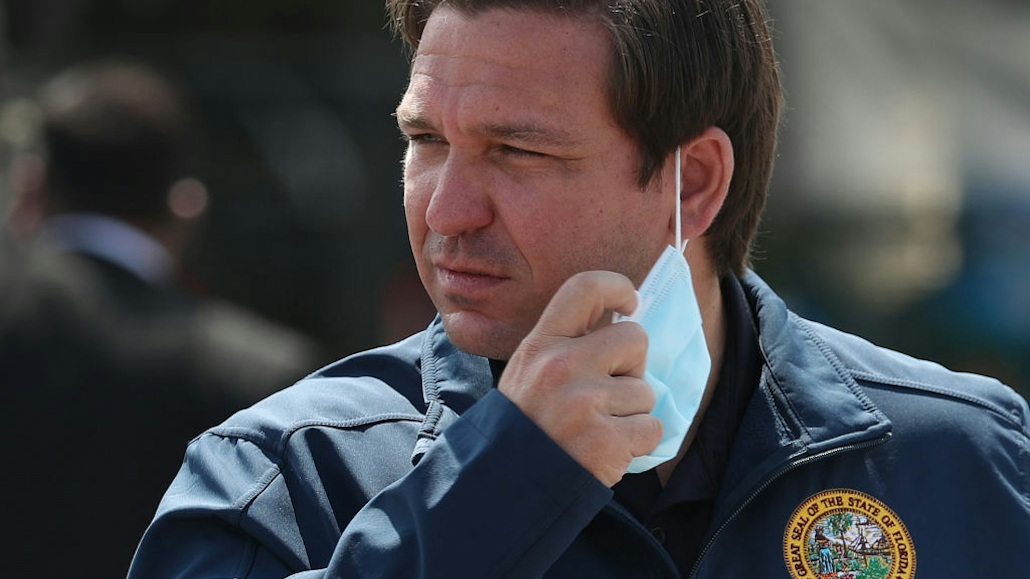 Florida Gov. Ron DeSantis takes his mask off as he prepares to speak during a press conference at the Hard Rock Stadium testing site on May 06, 2020 in Miami Gardens, Florida.