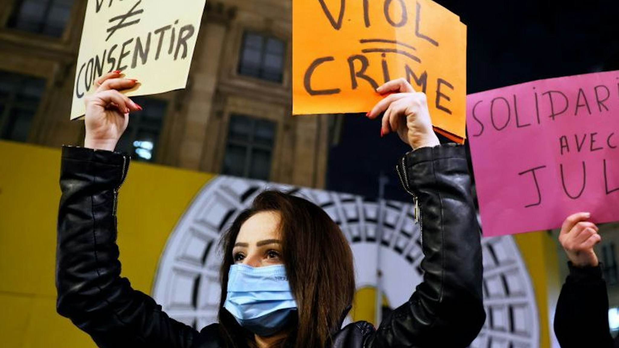 Protesters hold placards reading "Rape (does not equal) consent", "Rape = crime" and "Solidarity with Julie" on November 18, 2020, in Paris, during a demonstration called by feminist groups after a French court retained the legal classification of "sexual infringement", in the accusation of three firefighters over relations with a 14-year-old minor, "Julie", in 2009. - The Versailles court of appeal rejected on November 12 a request to reclassify the charges as "rape", retaining the classification of "sexual infringement". (Photo by Thomas SAMSON / AFP) (Photo by THOMAS SAMSON/AFP via Getty Images)