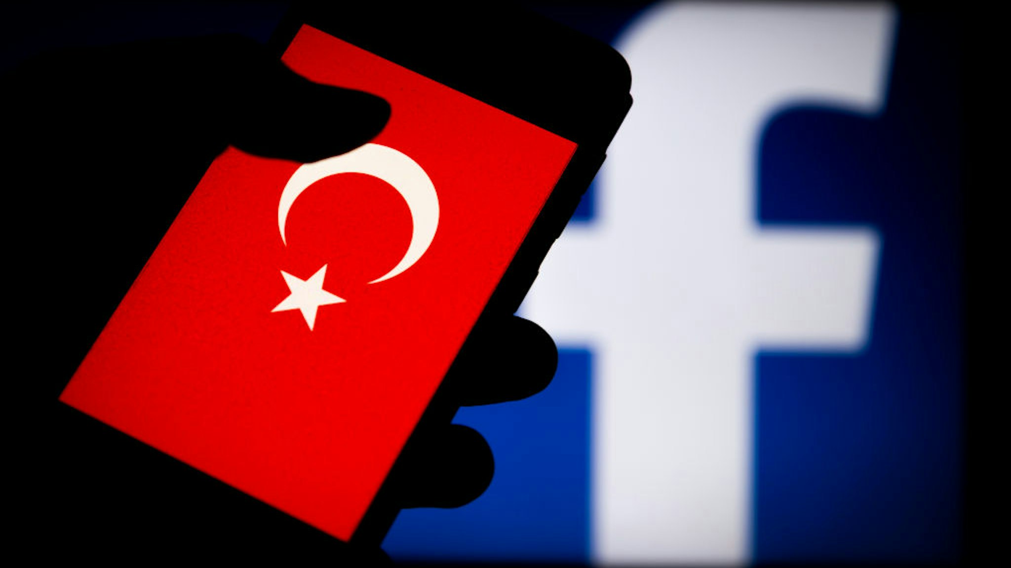 In this photo illustration a Turkish flag is seen displayed on a smartphone with a Facebook logo in the background.