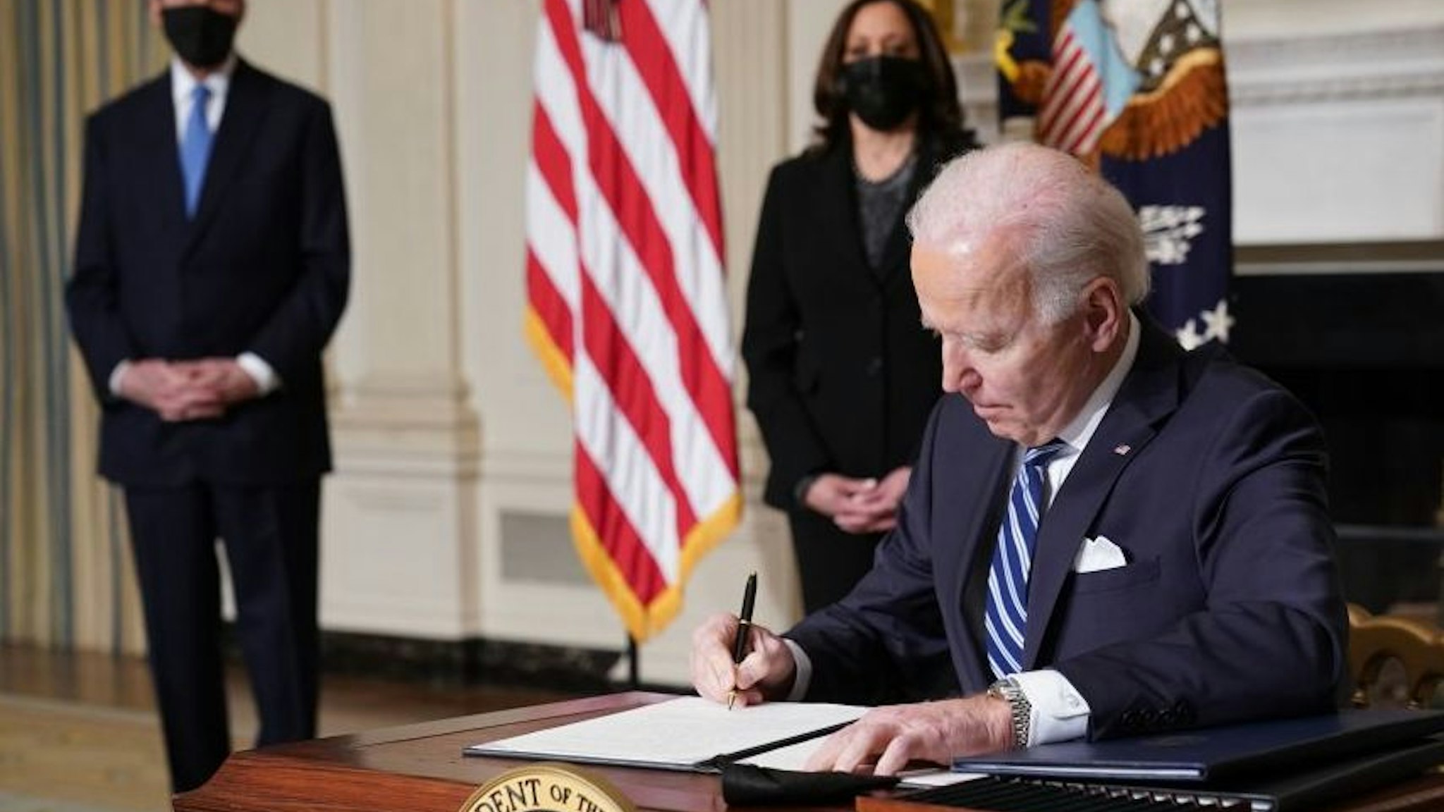 US Vice President Kamala Harris (2-L) and Special Presidential Envoy for Climate John Kerry (L) watch as US President Joe Biden signs executive orders after speaking on tackling climate change, creating jobs, and restoring scientific integrity in the State Dining Room of the White House in Washington, DC on January 27, 2021.
