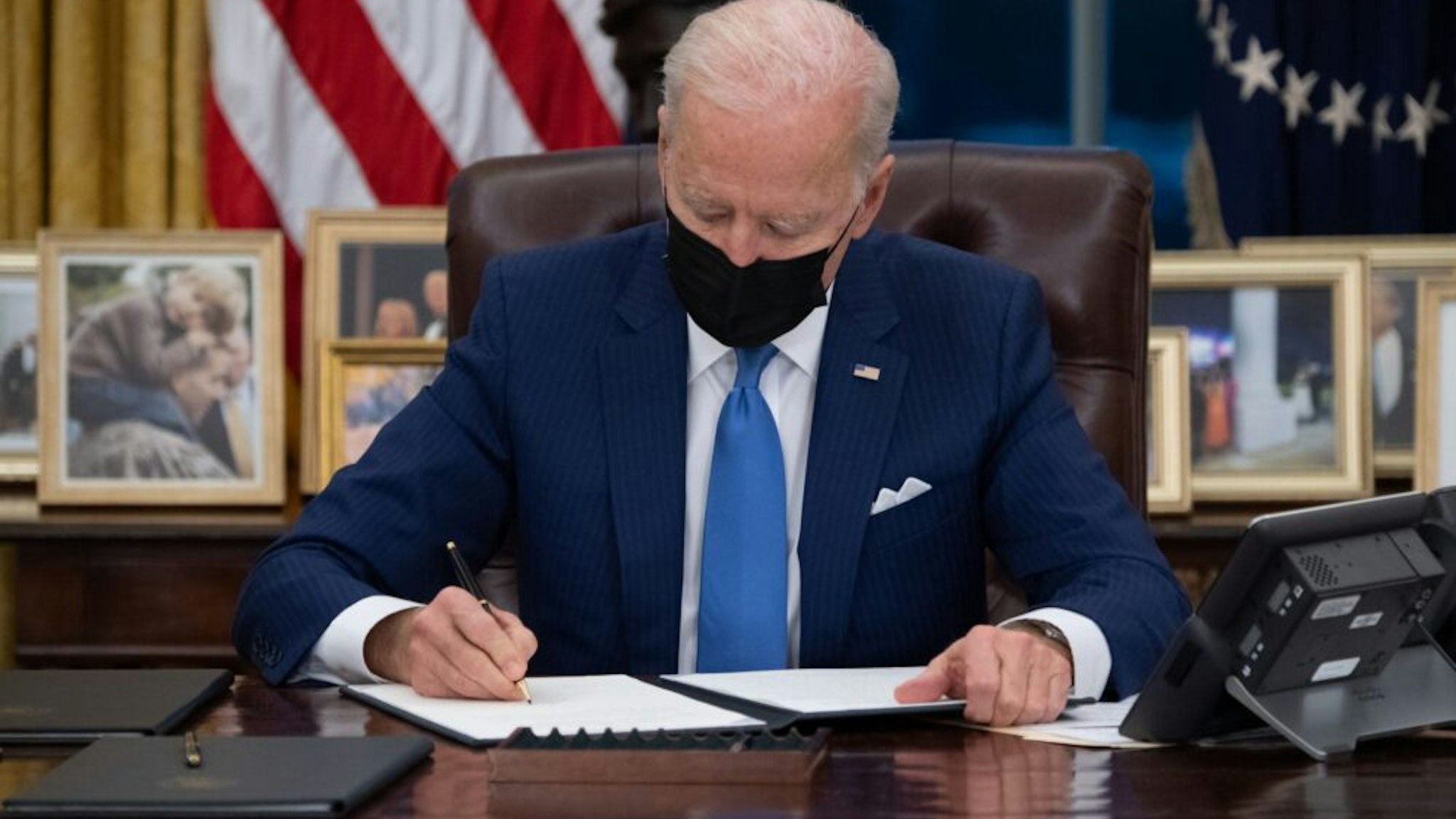 US President Joe Biden signs executive orders related to immigration in the Oval Office of the White House in Washington, DC, February 2, 2021.