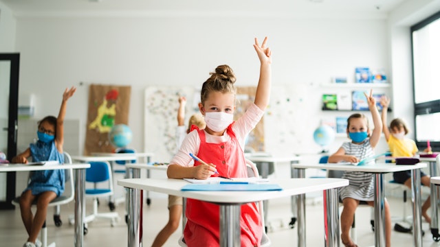 Small children with face mask back to school after coronavirus quarantine, learning. - stock photo
