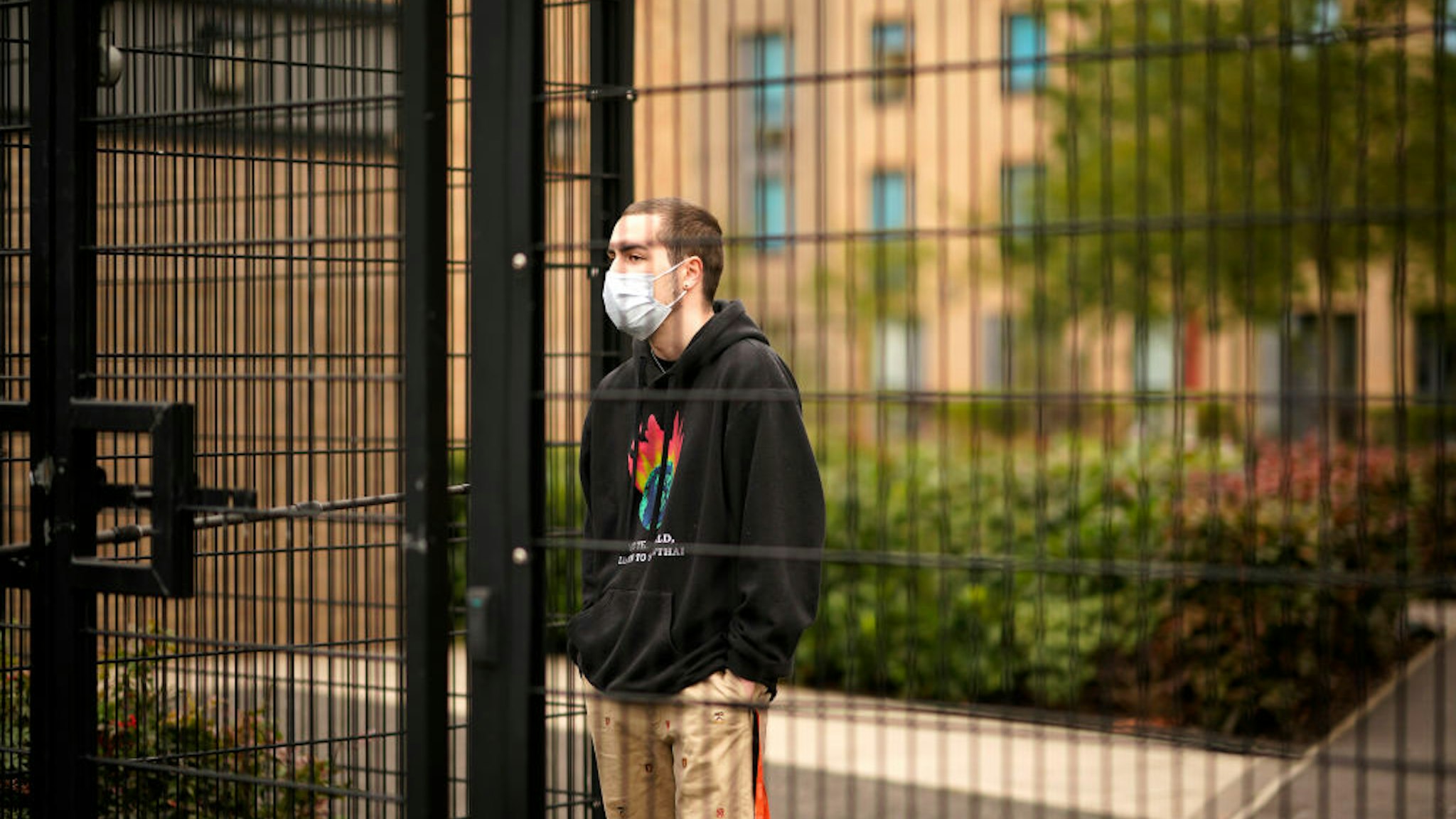 MANCHESTER, ENGLAND - SEPTEMBER 28: Students who are self-isolating stand behind the security fencing of theoir accommodation as they are interviewed by a television crew on September 28, 2020 in Manchester, England. Around 1,700 students across two student housing blocks were told to self-isolate after more than 100 students recently tested positive for Covid-19. The students were told to self-isolate for 14 days even if they were not experiencing symptoms. (Photo by Christopher Furlong/Getty Images)