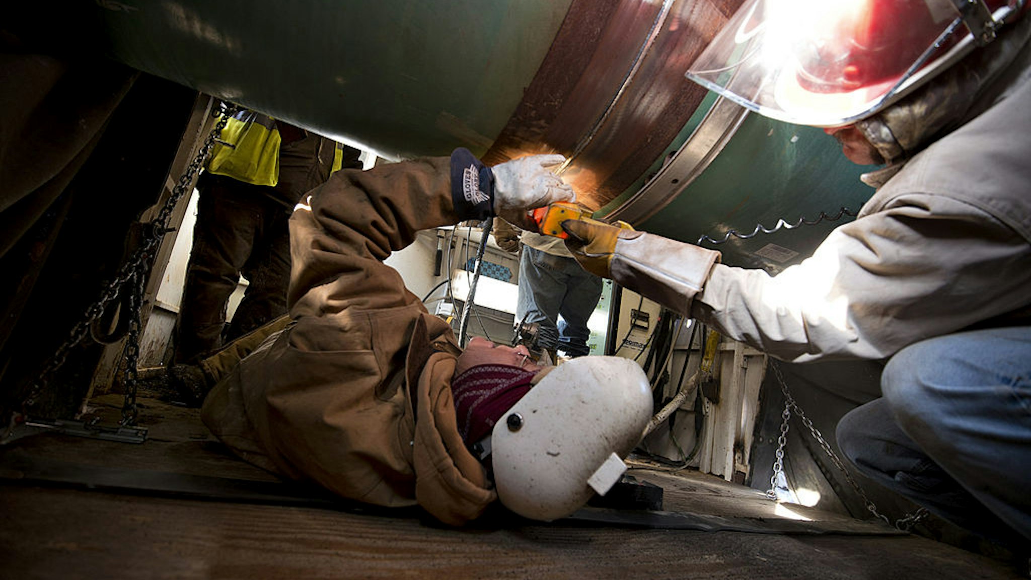 Workers inspect a weld on the joint between two sections of pipe on a Gulf Coast Project pipeline in Atoka, Oklahoma, U.S., on Monday, March 11, 2013.