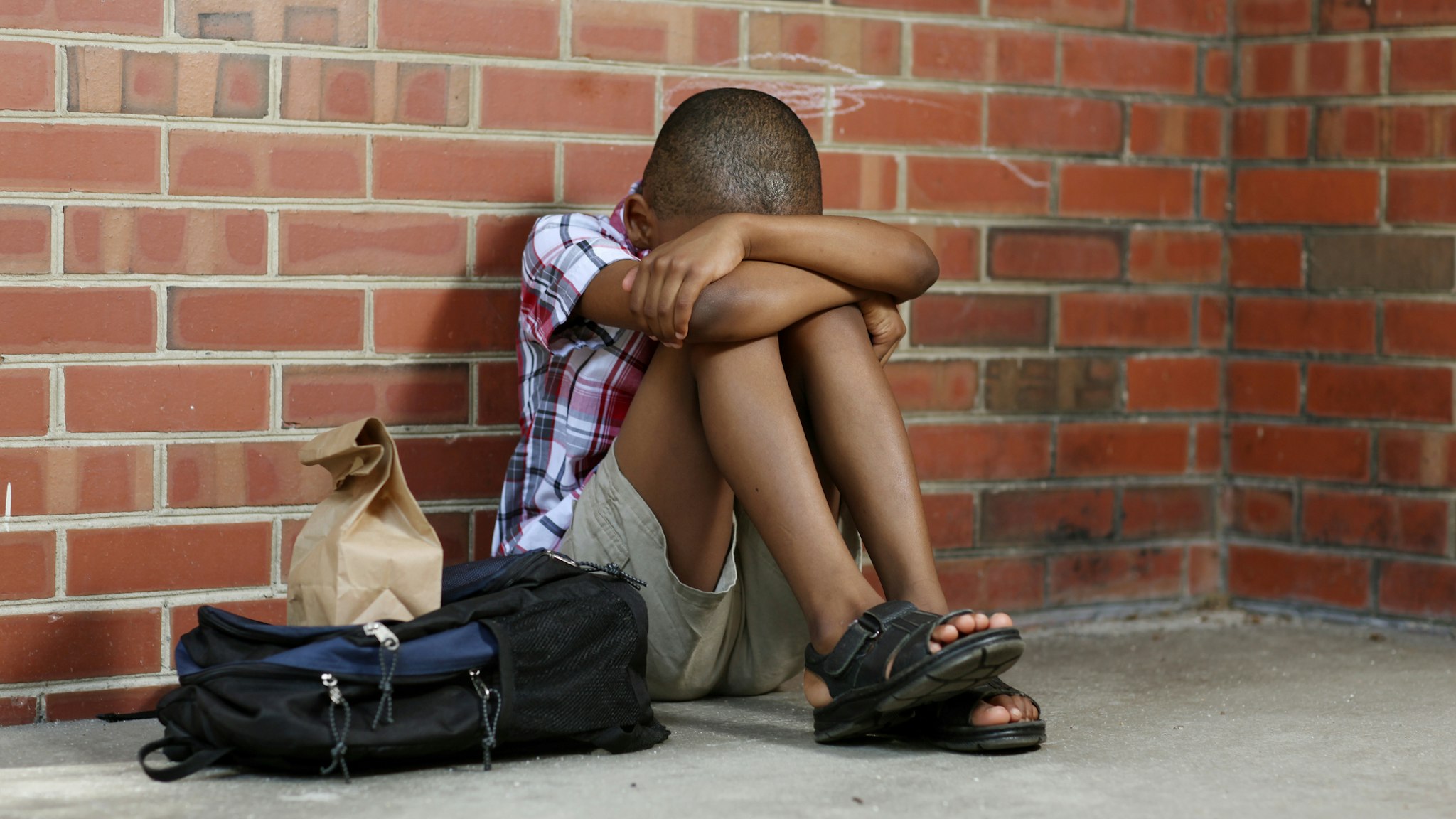 Sitting alone a poor child is bullied at school. - stock photo