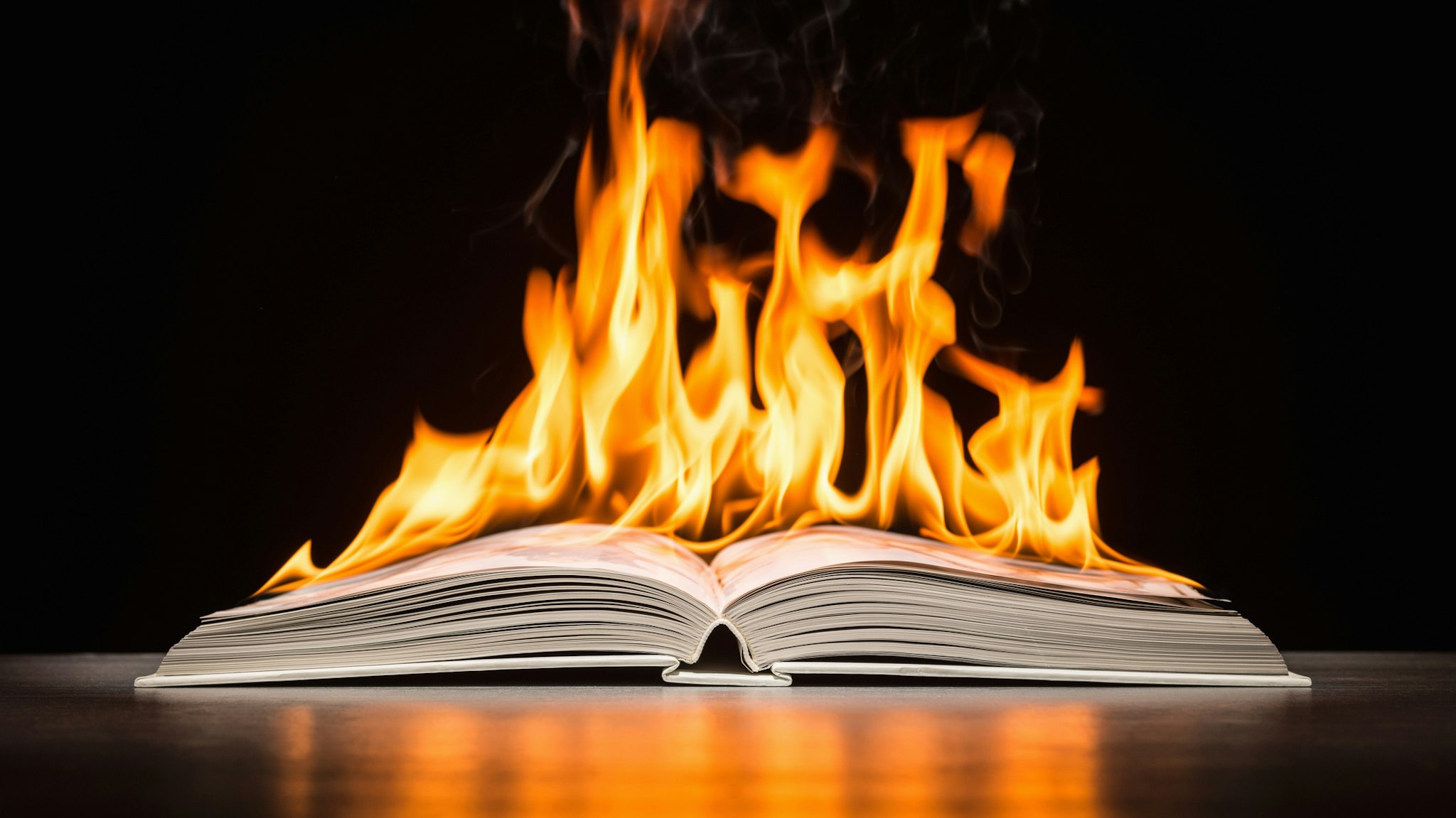 Open hard covered book engulfed in flame