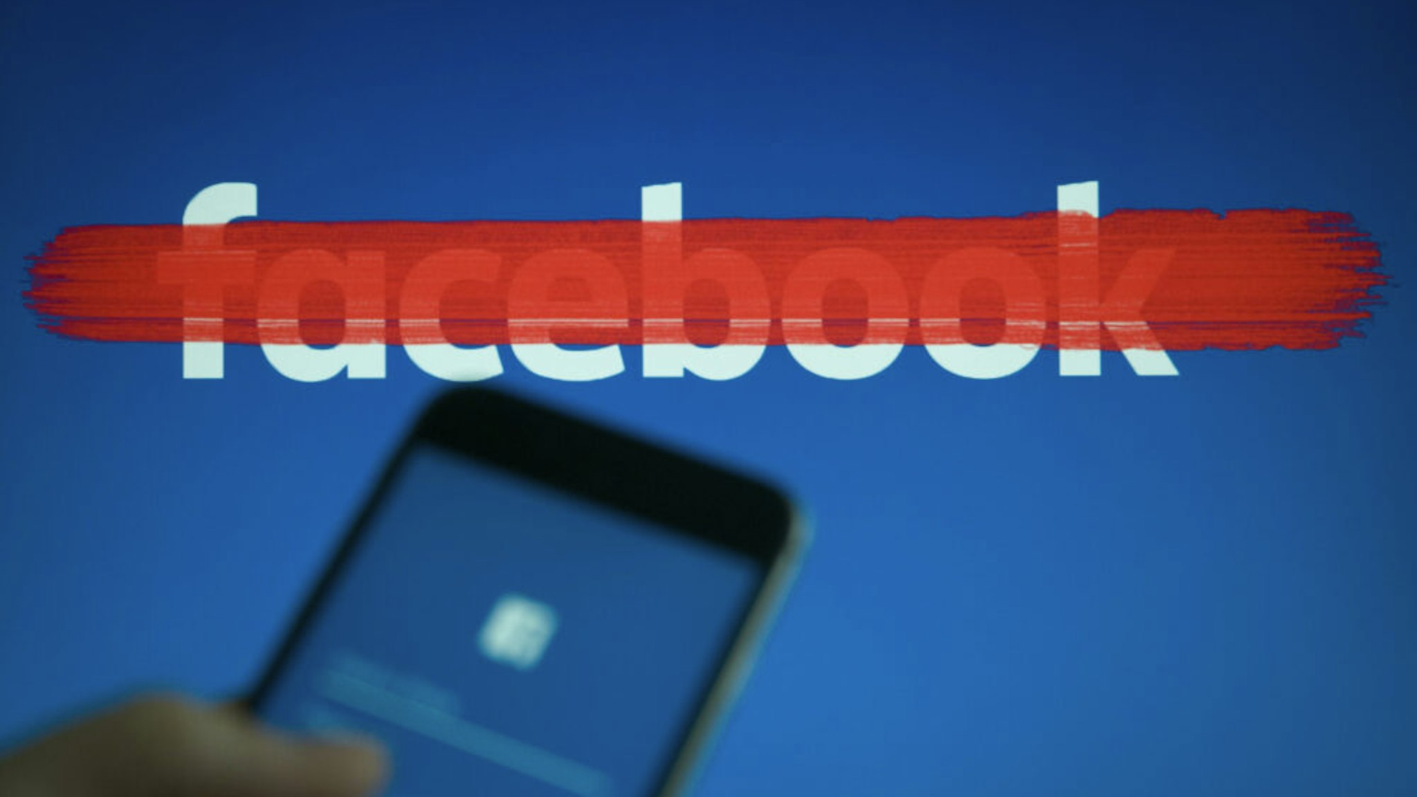 An iphone with a facebook login screen is seen with a striked out facebook logo in the background in this photo illustration on September 22, 2017.