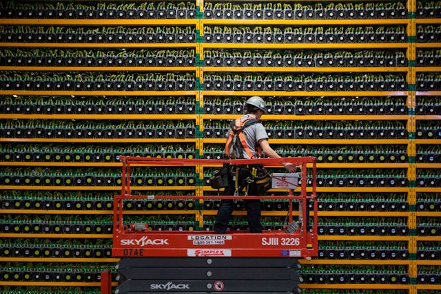 TOPSHOT - A technician inspects the backside of bitcoin mining at Bitfarms in Saint Hyacinthe, Quebec on March 19, 2018. - Bitcoin is a cryptocurrency and worldwide payment system. It is the first decentralized digital currency, as the system works based on the blockchain technology without a central bank or single administrator. (Photo by Lars Hagberg / AFP) (Photo by LARS HAGBERG/AFP via Getty Images)