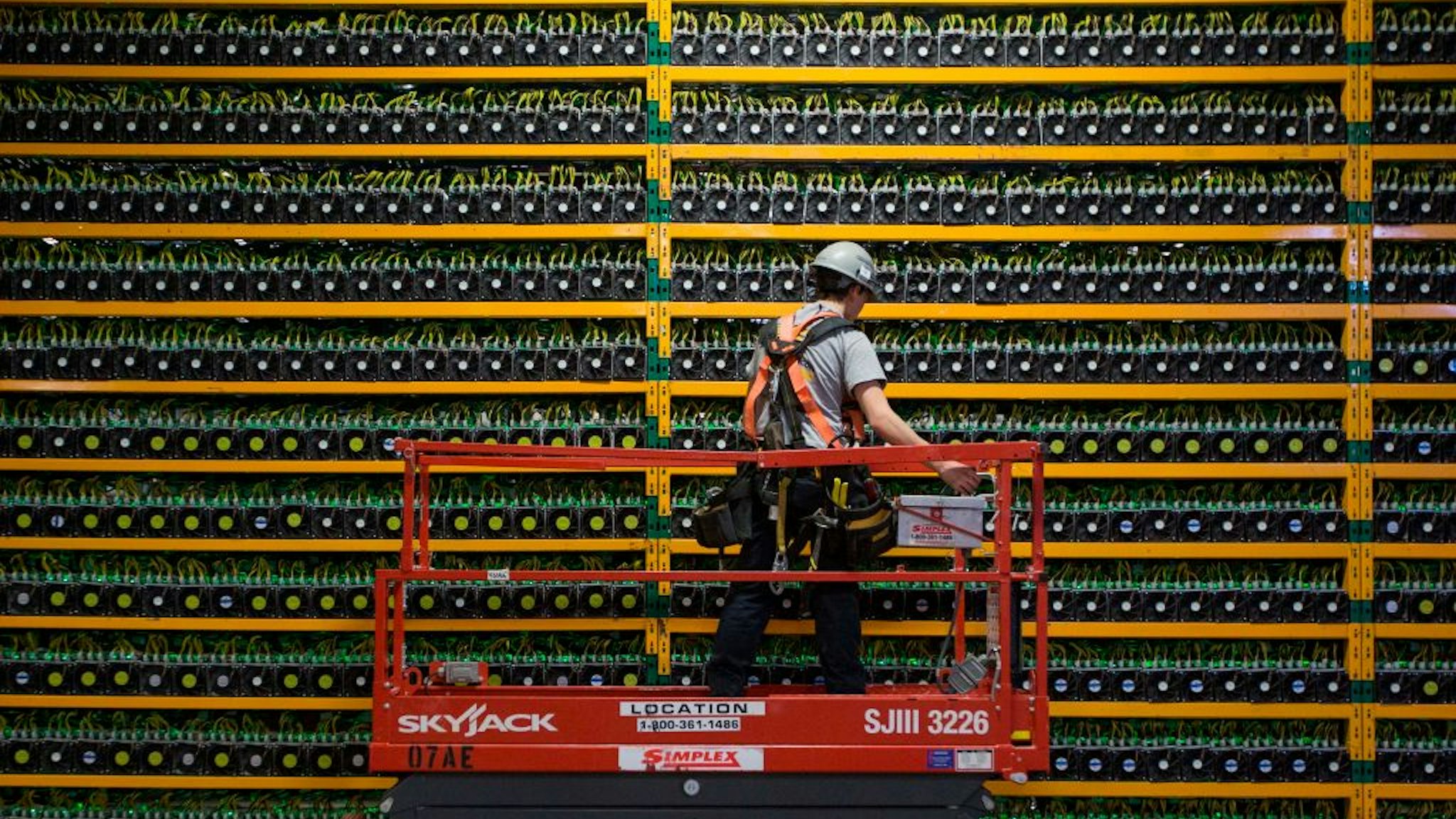 TOPSHOT - A technician inspects the backside of bitcoin mining at Bitfarms in Saint Hyacinthe, Quebec on March 19, 2018. - Bitcoin is a cryptocurrency and worldwide payment system. It is the first decentralized digital currency, as the system works based on the blockchain technology without a central bank or single administrator. (Photo by Lars Hagberg / AFP) (Photo by LARS HAGBERG/AFP via Getty Images)