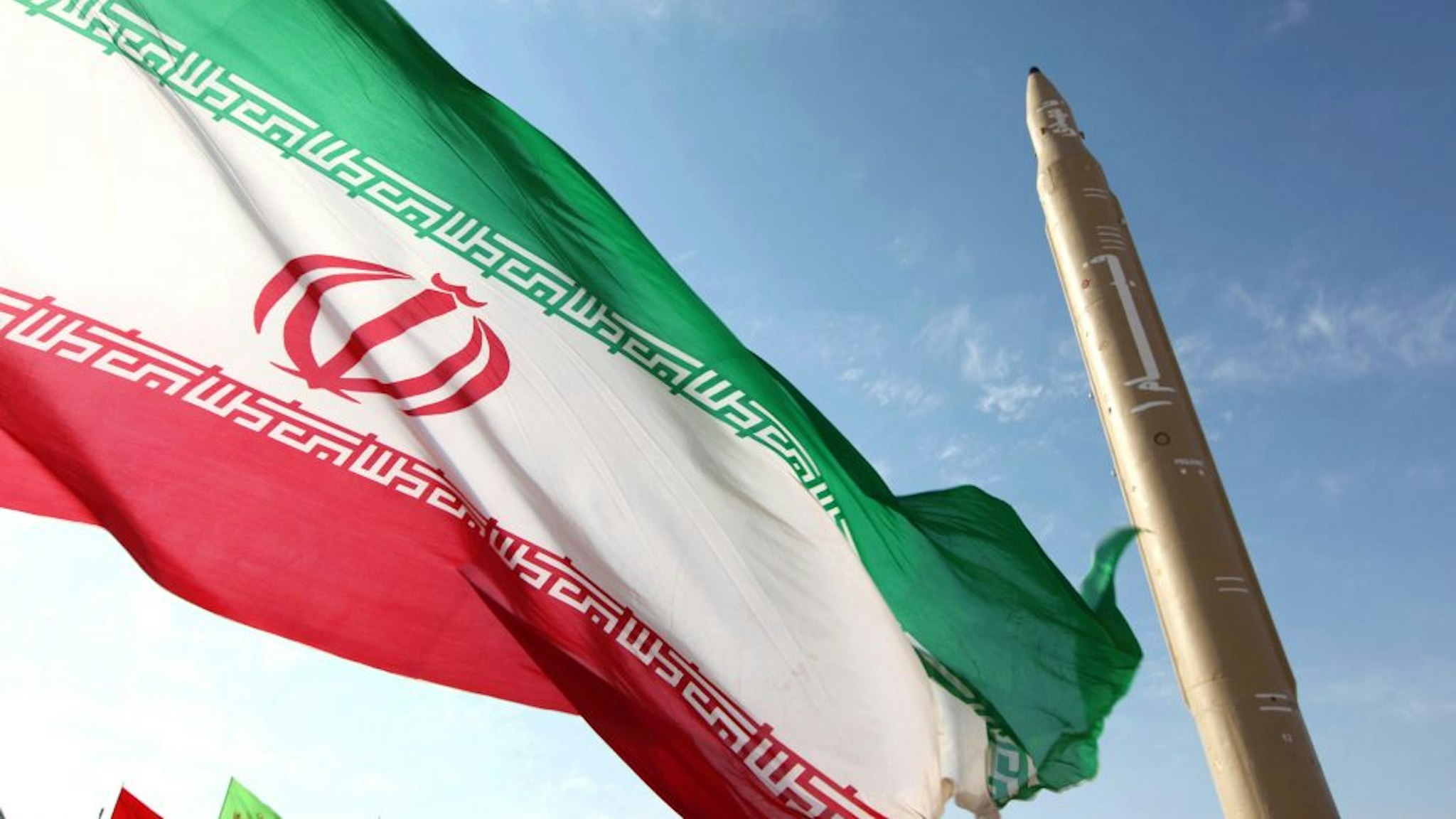 A picture taken on August 20, 2010 shows an Iranian flag fluttering at an undisclosed location in the Islamic republic next to a surface-to-surface Qiam-1 (Rising) missile which was test fired a day before Iran was due to launch its Russian-built first nuclear power plant. Iranian Defence Minister Ahmad Vahidi said the missile was entirely designed and built domestically and powered by liquid fuel.