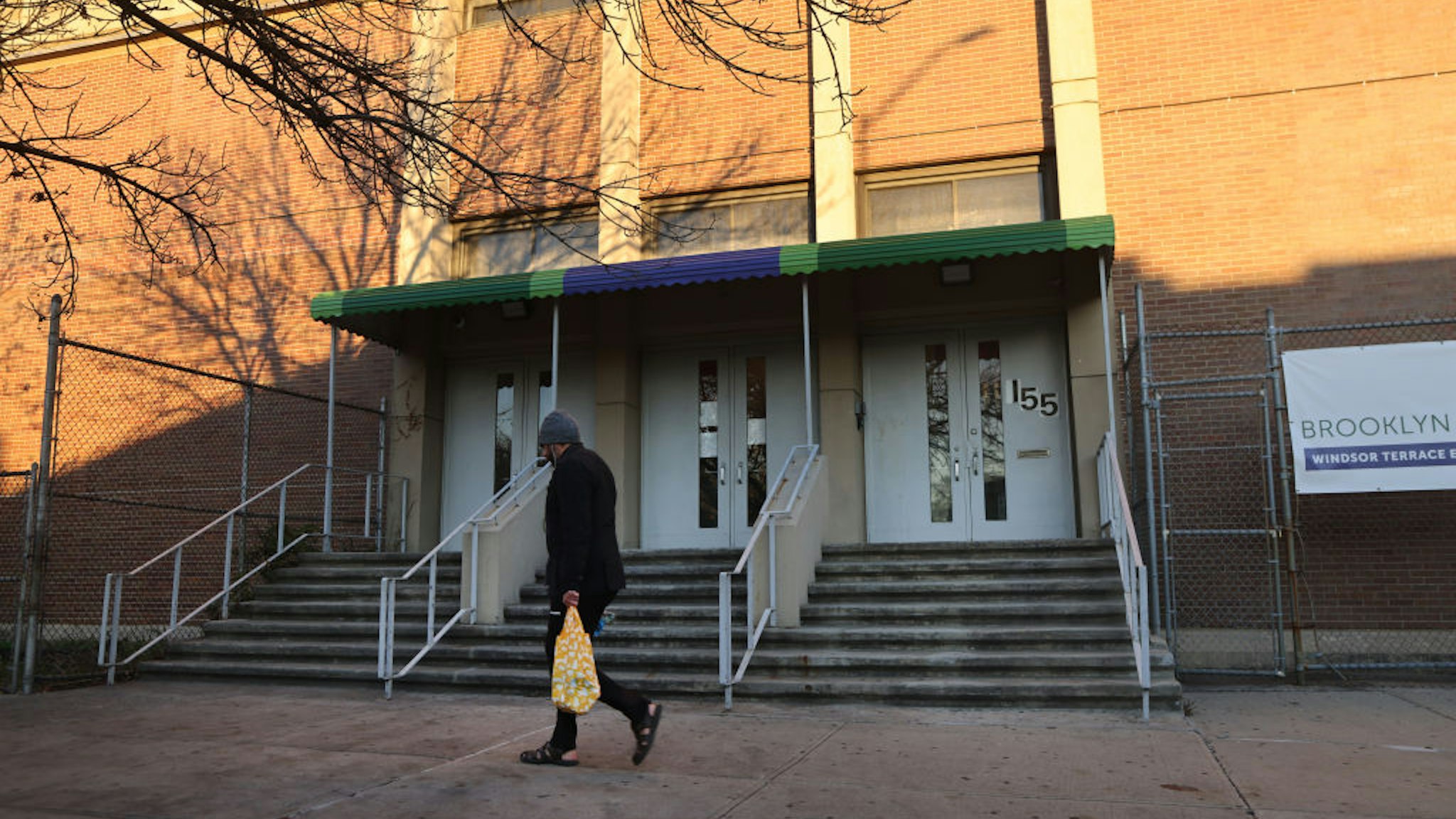 A person walks by a public school in Brooklyn on November 18, 2020 in New York City. Public schools in New York City, the largest school district in the nation, will close again on Thursday, officials have said after the city reached a 3% Covid test positivity rate.