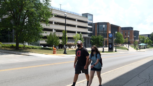 Students wearing protective masks walk through campus during the first of classes at Ohio State University in Columbus, Ohio, U.S., on Tuesday, Aug. 25, 2020. Some of Ohio's colleges and universities have begun moving students in, but the navigation of a school year amid a pandemic is still a balancing act.